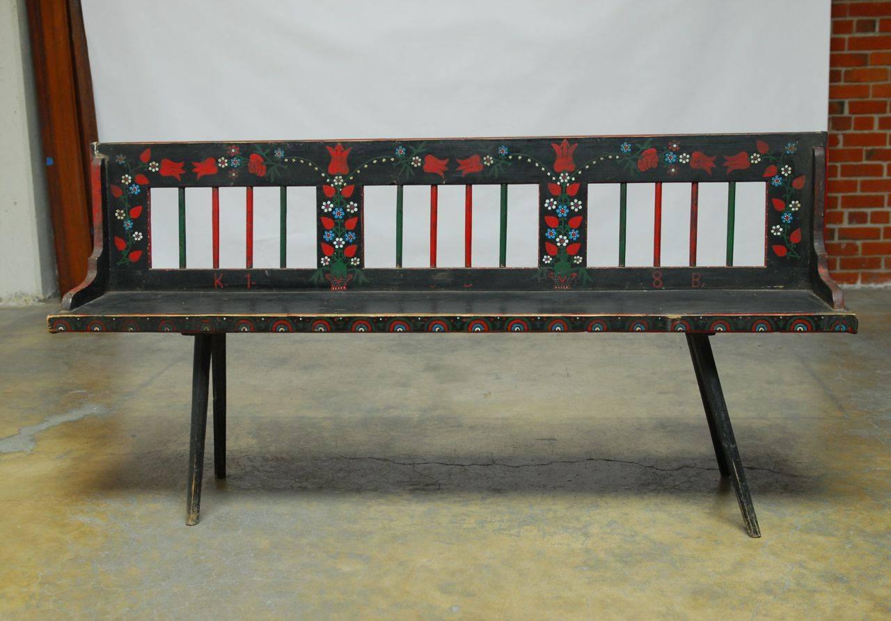 Charming polychrome painted bench decorated with stylized floral patterns over a black ground. Features delicate spindle legs and back rest. This rare bench shows the creativity of the individual artist while displaying the regional style of Eastern