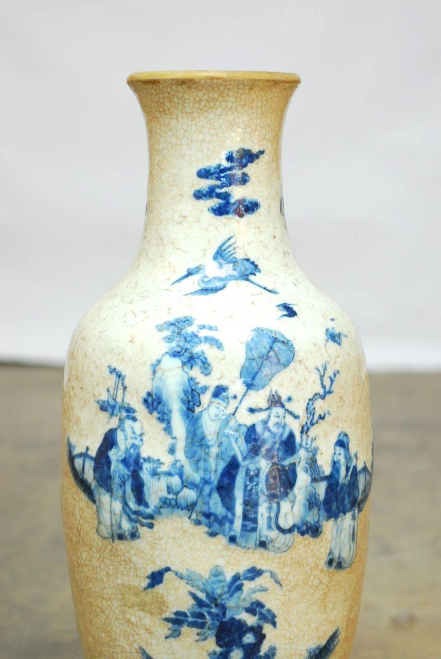 Impressive hand-stamped vase with a crackle glaze featuring blue and white underglaze depiction of three immortals in a garden scene. Small loss of applied handles on each side of neck. Supported by a carved wood Stand with a dark finish.
