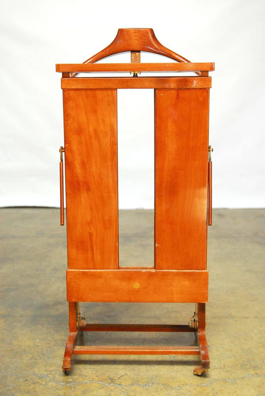 Italian trouser press constructed from cherry by Fratelli Reguitti and signed on the front. Large coat hanger and area for change and cuff links. Sits on casters and has a polished lacquer finish. 
