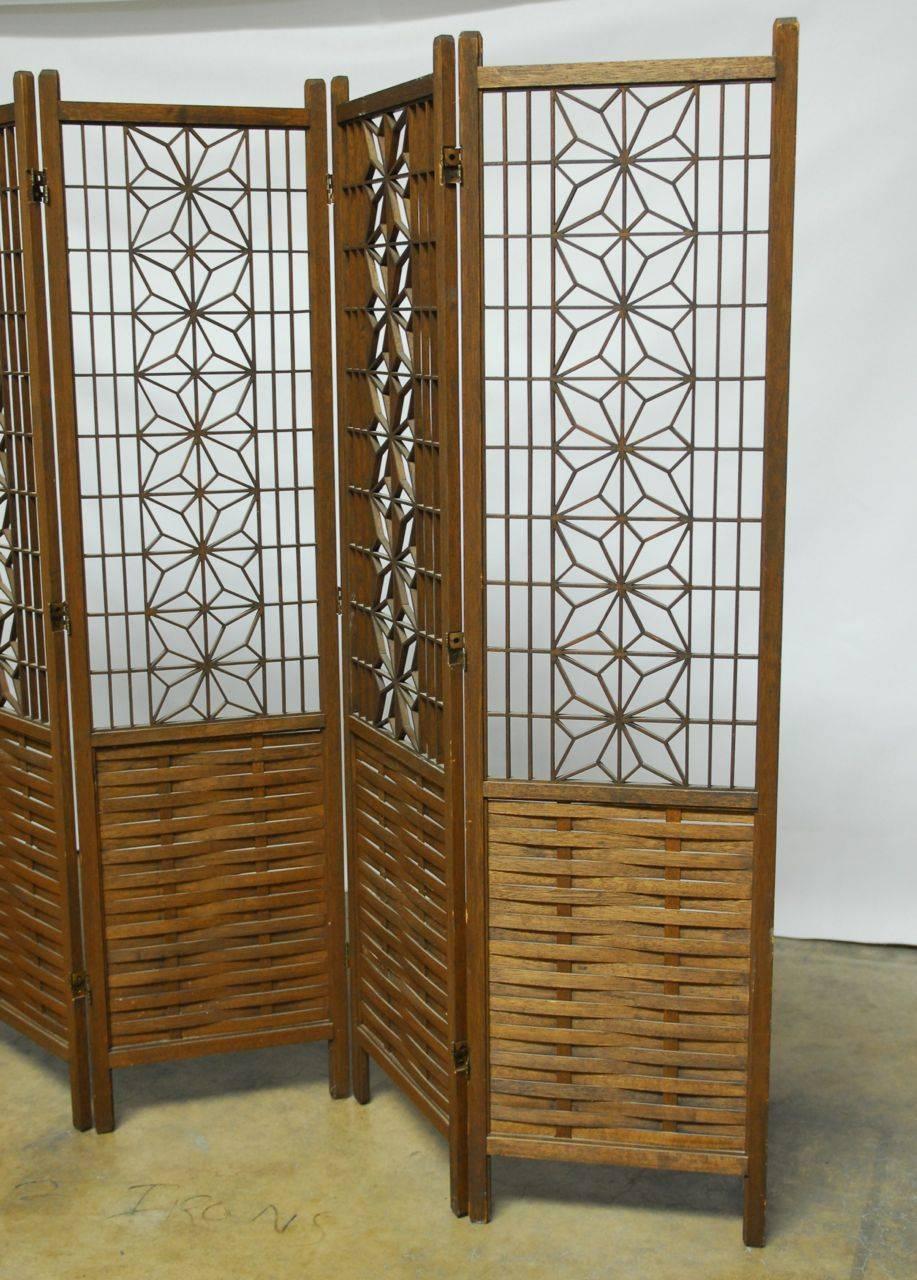 Gorgeous six-panel folding room divider featuring a captivating geometric pattern top centered by stars made of diamond shapes. The bottom half of the screen features woven wood slats. Would make a fabulous wall decoration or headboard mounted flat.