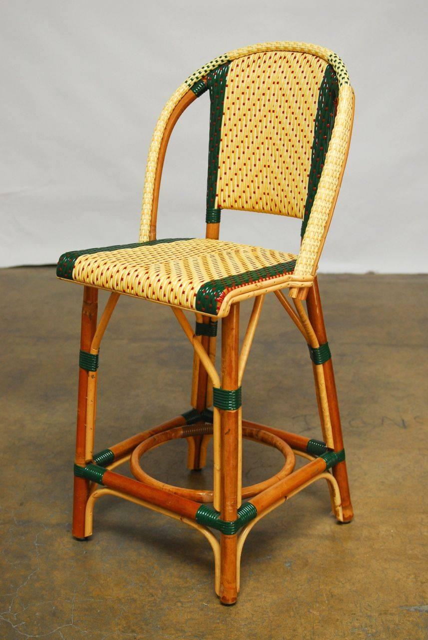 Pair of classic French rattan bistro chairs handmade by Maison J. Gatti featuring a woven seat and back in cream, green and red. These virtually indestructible chairs have been made for Paris bistros since 1920. Iconic design with strong hand made