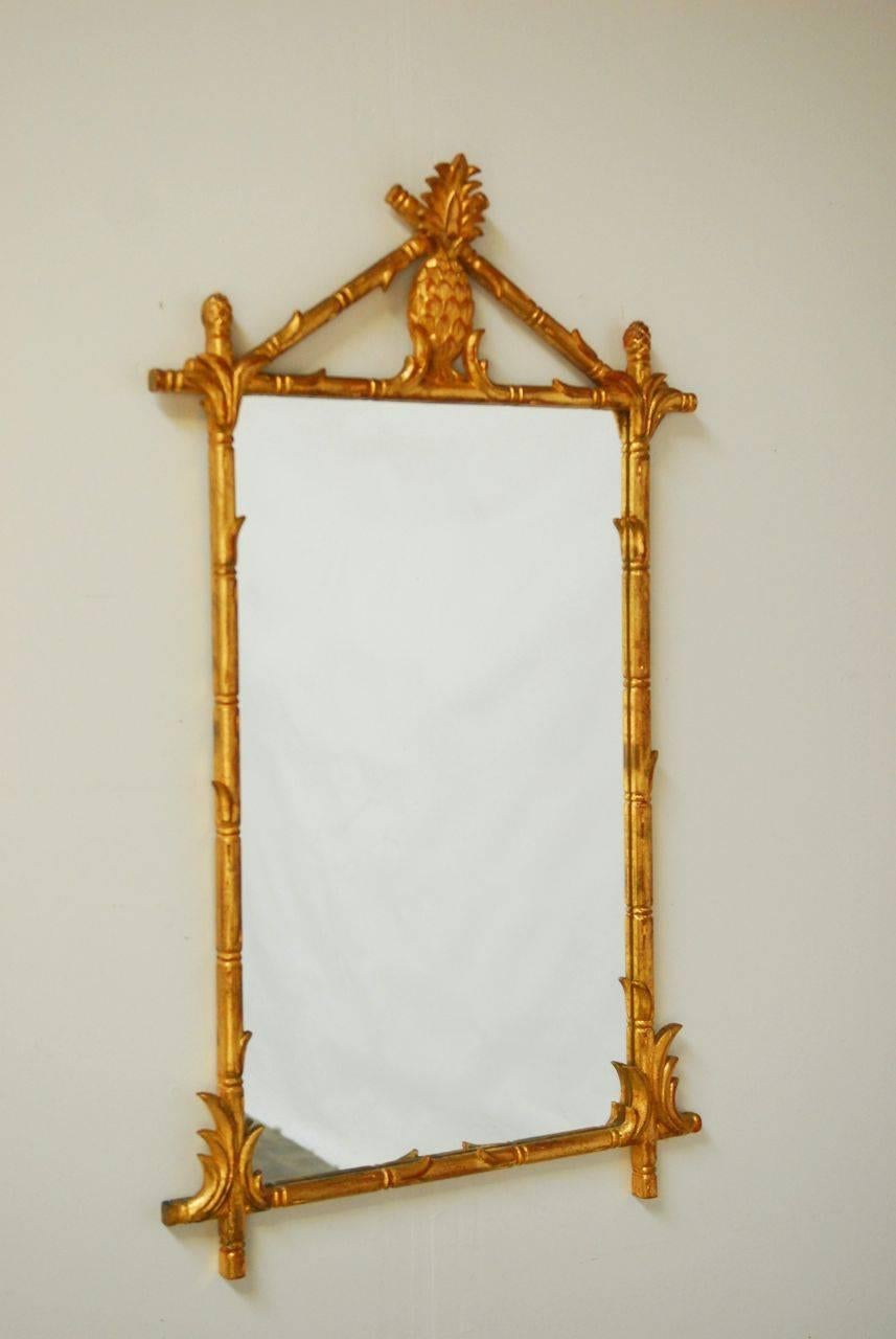 Fantastic designer mirror in a Classic Chinese Chippendale design. Features a faux bamboo carved frame with a pineapple ornamentation and leafed corners. Hollywood Regency style with a Classic giltwood finish.