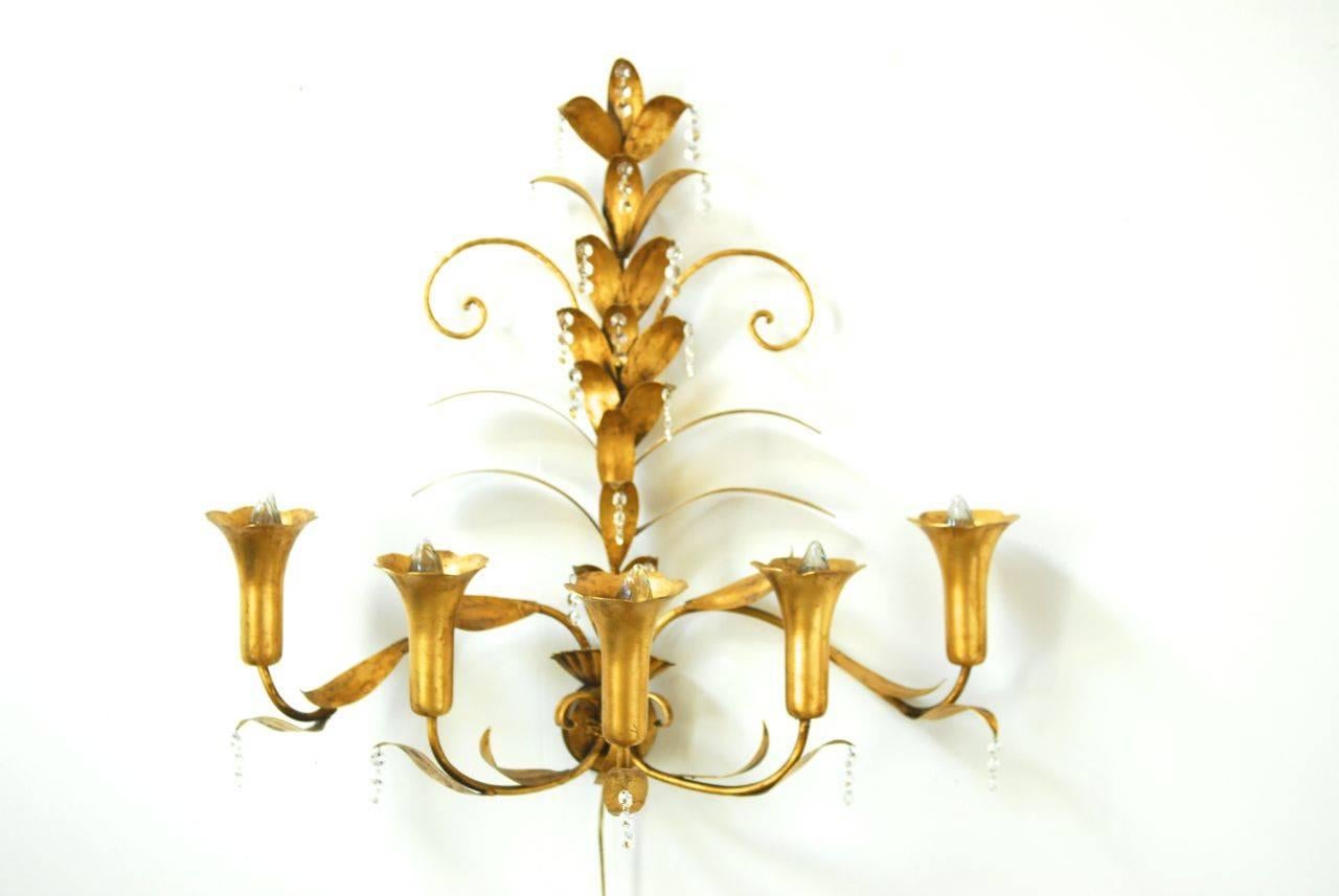 Elegant floral wall sconce featuring five tulip form lights and a gilt covered frame. Hollywood Regency style highlighted by strands of cut crystal drops. Sold new in San Francisco by American Interiors.
