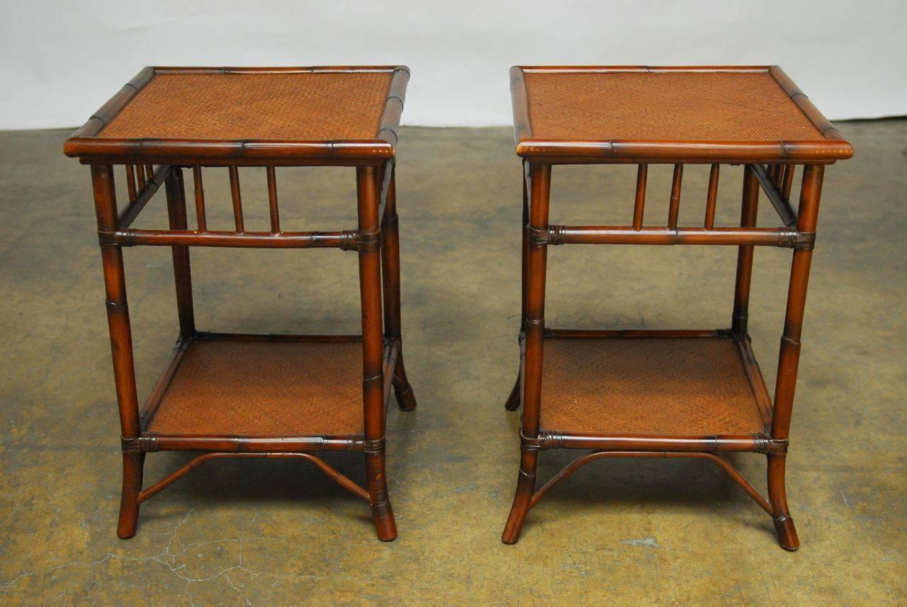 Handsome pair of rattan side tables featuring two tiers with a lacquered sea grass top. Open fretwork decorated sides with leather strapping and a rich finish.