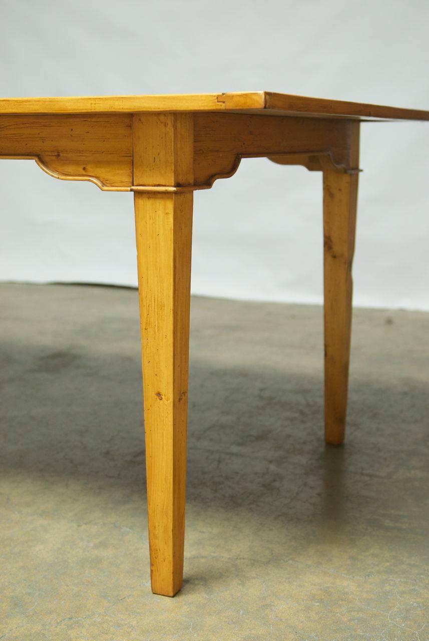 Impressive Italian farmhouse table featuring a wood plank top and tapered legs with a shaped apron. The pine has been lightly distressed and there is a decorative narrow carved border on the apron edge that goes around the table and gives the table