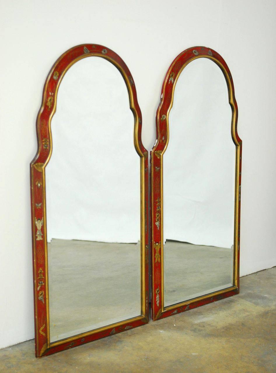 Fabulous pair of hand-painted red lacquer mirrors by Friedman Brothers. Featuring gilt trim and decorated in an oriental motif with Chinese characters and foliage on the borders. Fine, hand-formed beveled glass adds a distinctive, refined look to