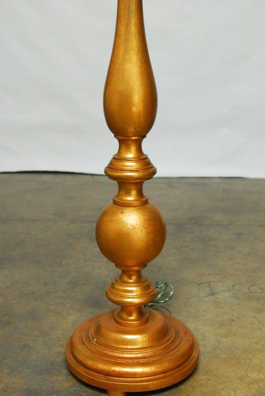 Lavish pair of Pricket style Italian candlestick floor lamps featuring a painstaking hand gilt finish. Baluster style form with a large round base and faux candle on top. Does not include harps or finials.