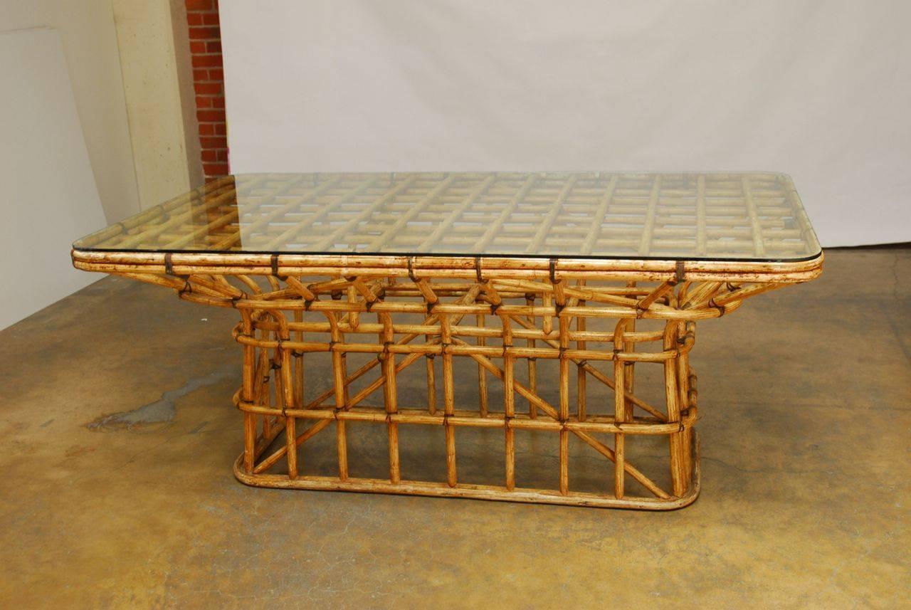 Extraordinary dining table constructed of bent bamboo with leather strapping. The rare table features an open lattice design that lends a distinctive style and complexity. The base is an intriguing cage of stretchers and supports connected to a