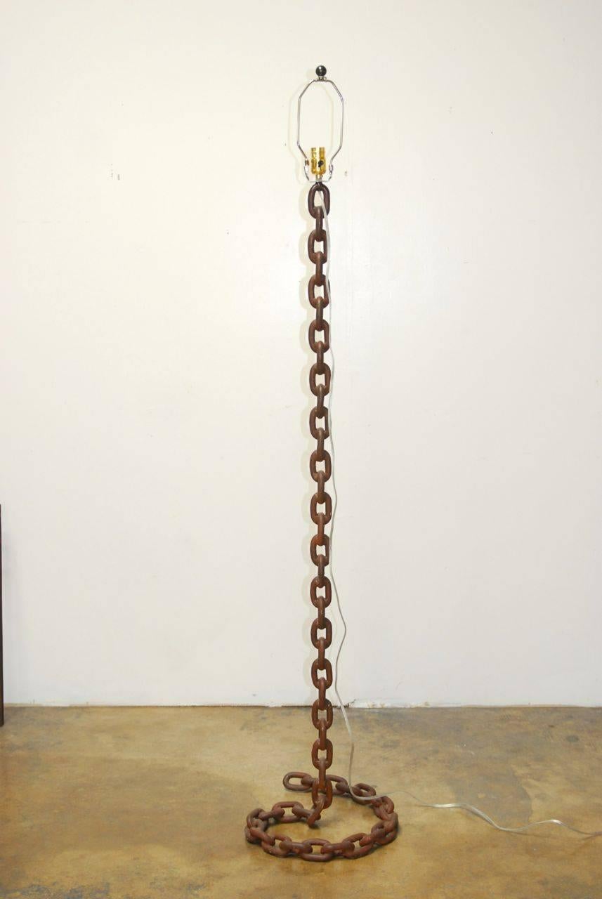 Unique floor lamp made of thick nautical chain links that swirl to make the base. Inspired by a Marrakech snake charmer this lamp features a rusty finish on the iron links. Includes a large barrel shade in linen with a ball finial. Design by Barry