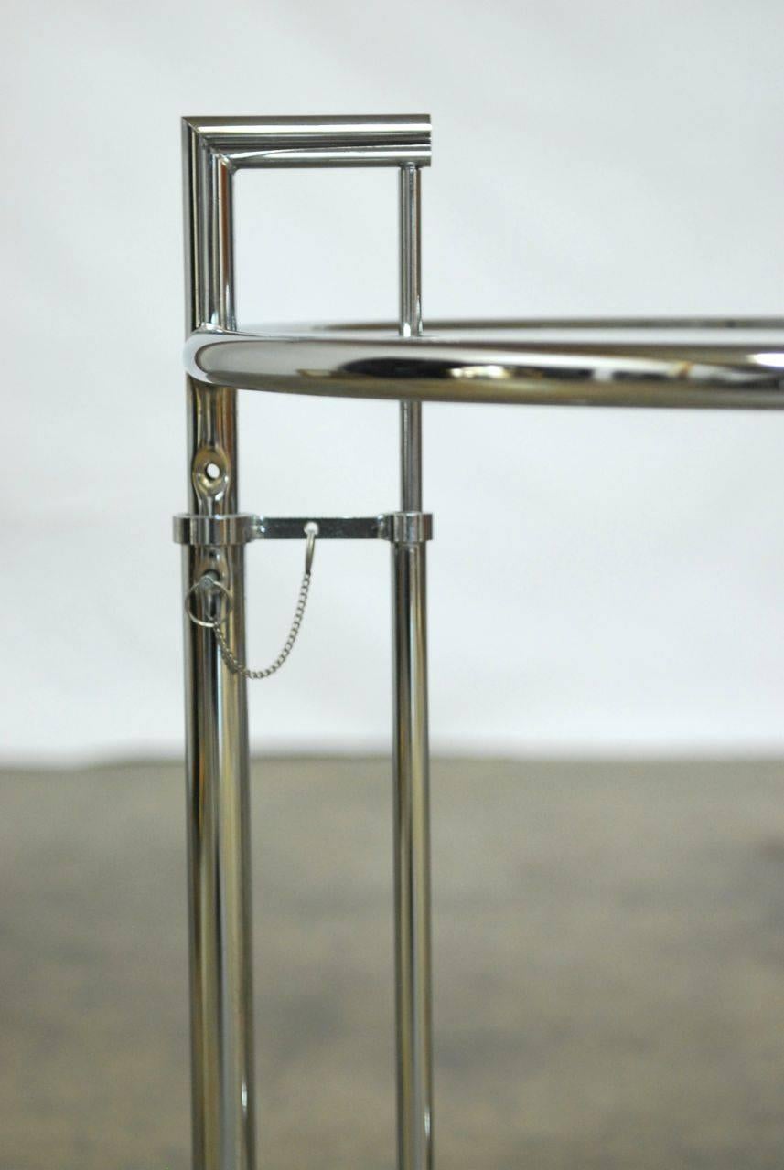 Fabulous pair of E1037 chrome and glass side tables featuring multi-level height-adjustment attributed to Eileen Grey. Iconic Mid-Century Modern style constructed of powder coated and chromed tubular steel. Raises up to 38