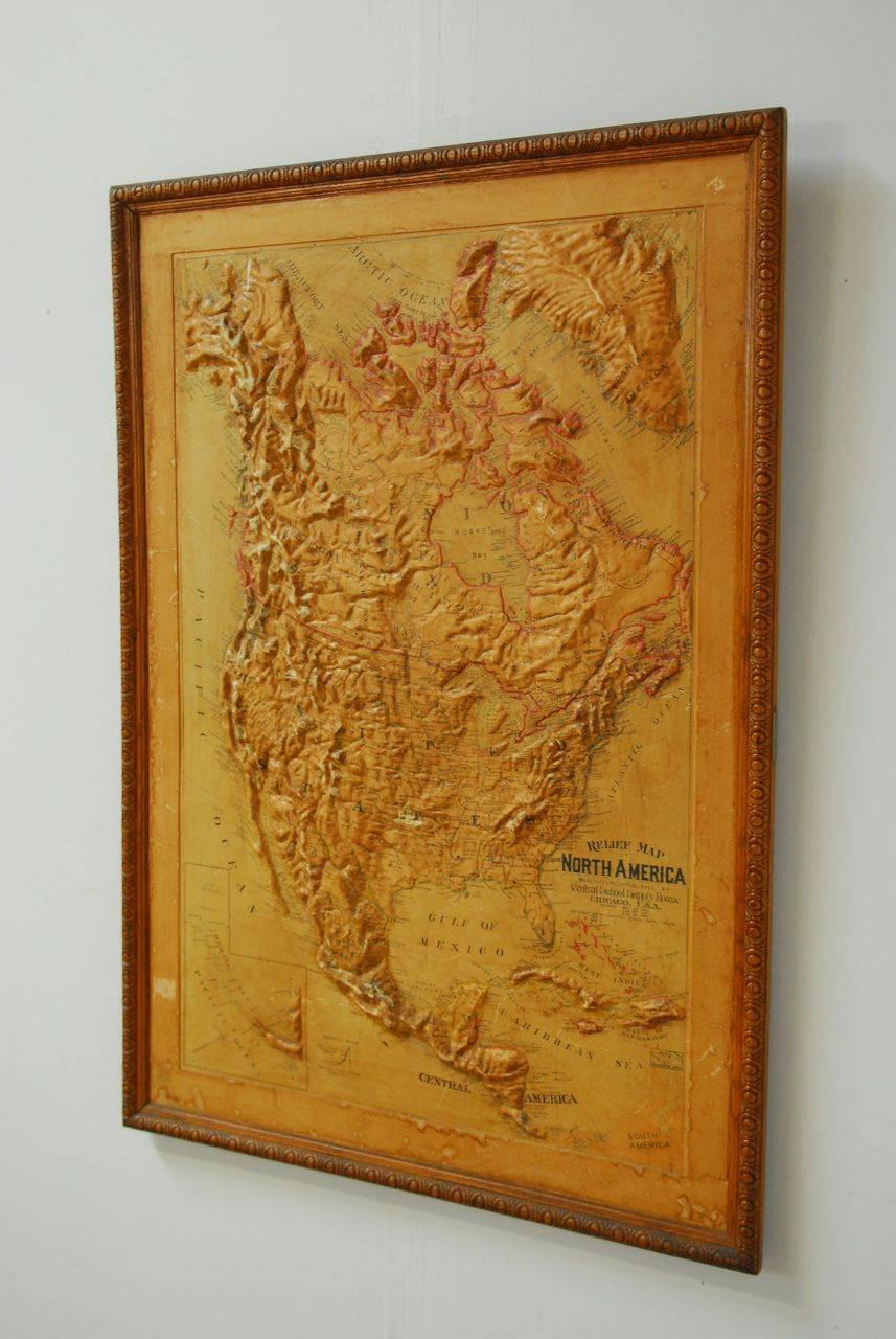 Early 1900s relief map of North America including Canada, Greenland, Mexico and Central America. Mounted on board and set in a carved oak frame. Produced by Atlas School Supply Chicago, Illinois.