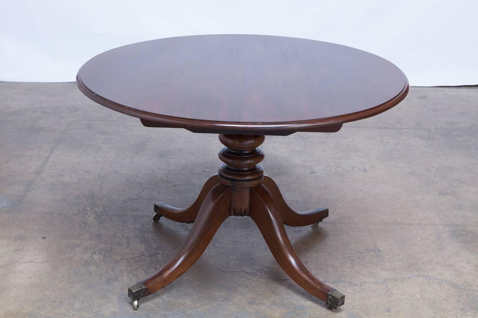 Elegant round tilt-top Mahogany breakfast or dining table made in the George III period. Features four tapering, splayed legs which terminate in brass toe caps and casters supporting a lovely turned pedestal. All original tilt mechanism hardware