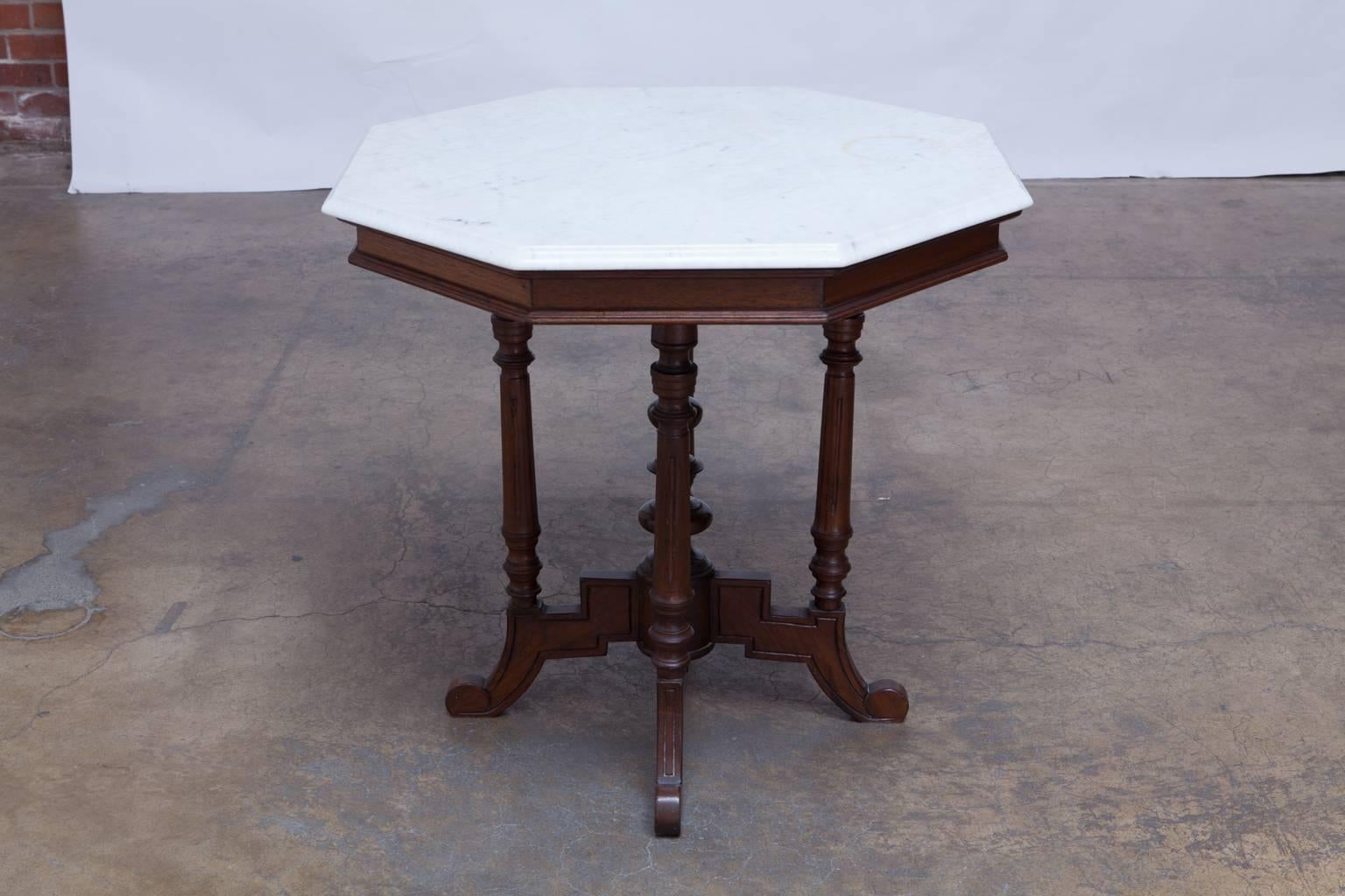 Distinctive marble-top octagonal center table featuring a well-carved mahogany base with geometric feet, turned legs, and stacked sphere centerpiece. Beautiful conforming octagonal white marble-top with an ogee edge profile.