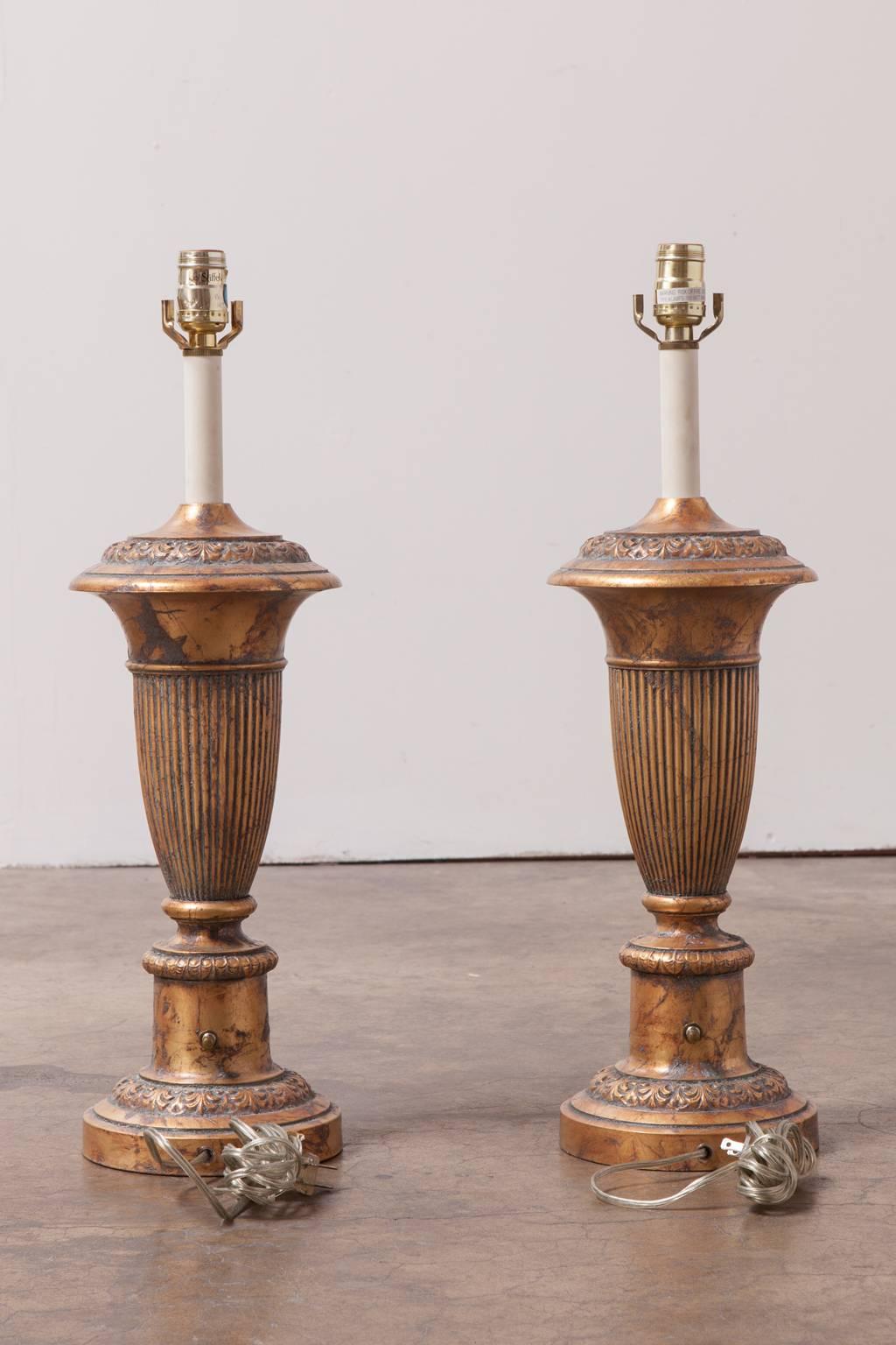Lavish pair of solid brass urn form table lamps with a patinated finish by Stiffel. Very heavy and solid with a neoclassical motif. Harps and finials not included. Excellent condition.