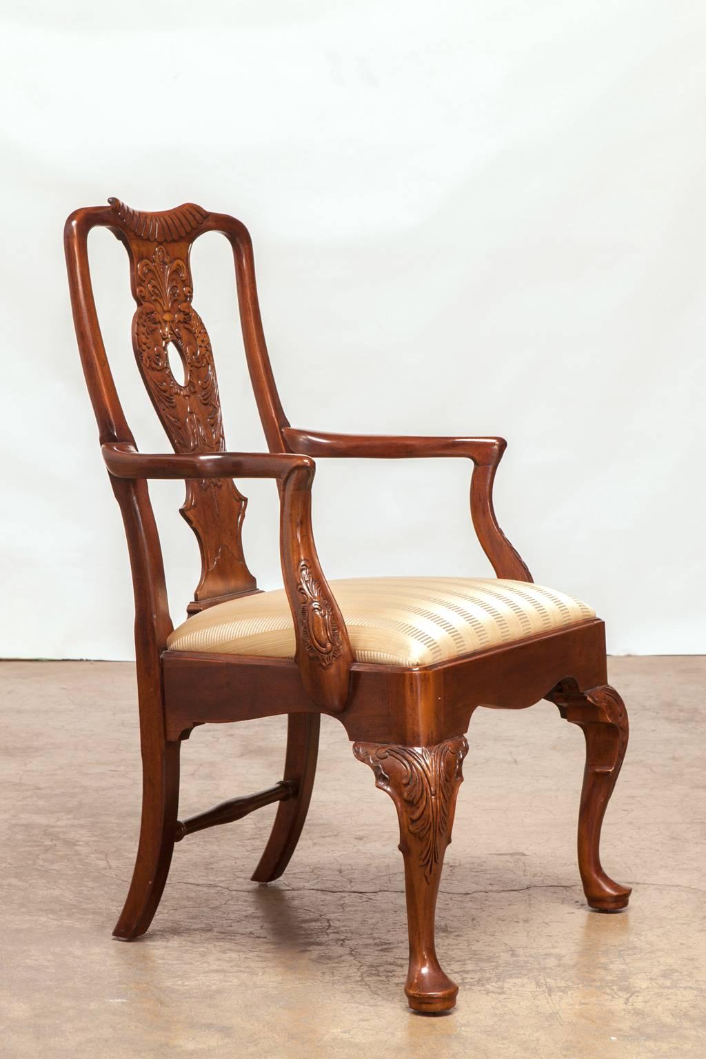 Remarkable set of 12 hand-carved mahogany dining chairs made in the Georgian style by Henredon. Featuring an intricately carved back splat with shell cartouches and supported by cabriole legs with pad feet. Set consists of ten side chairs and two