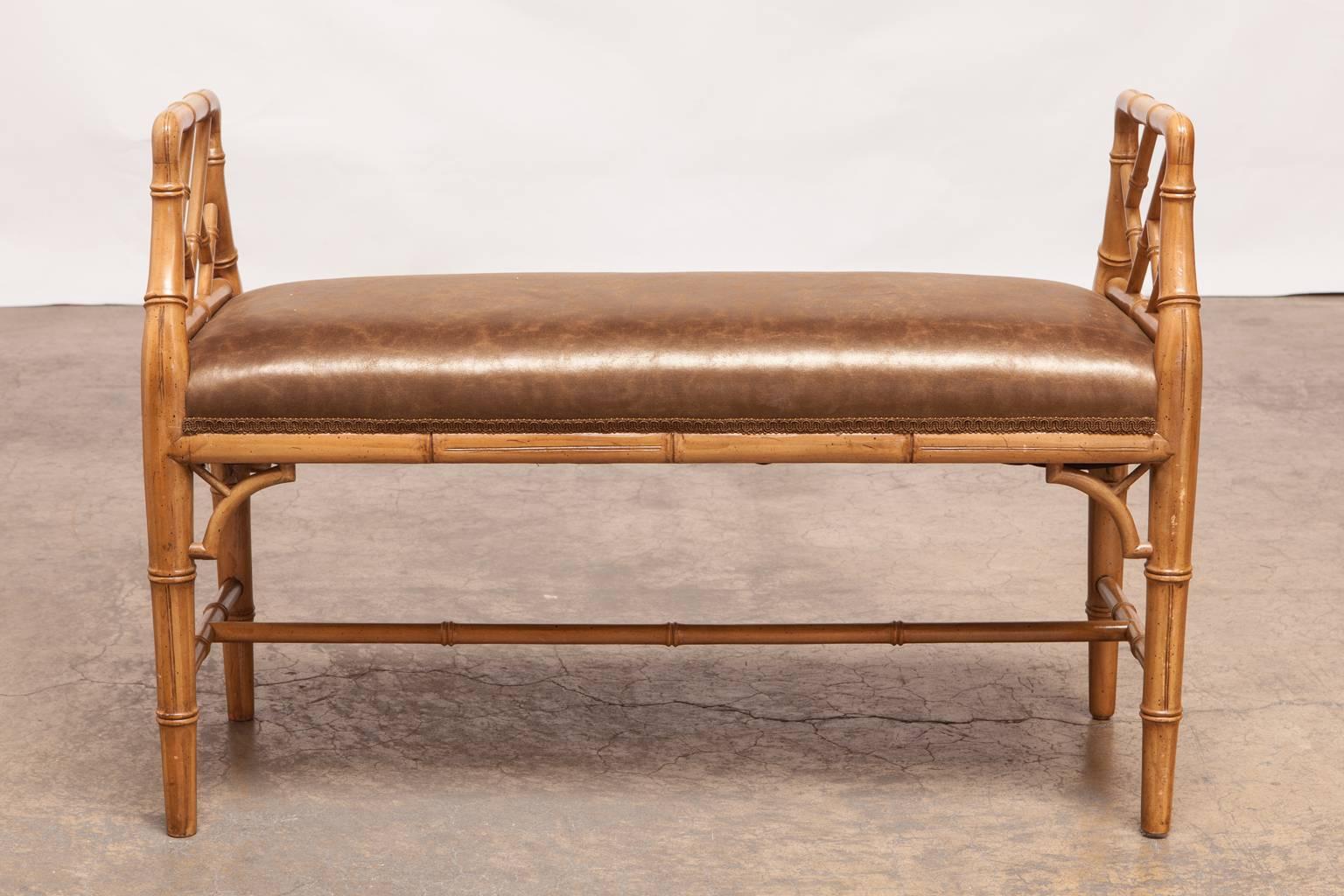 Stylish window bench made in the Chinese Chippendale style featuring an open fretwork design on both ends and decorative spandrels. Upholstered in rich marbled faux leather.