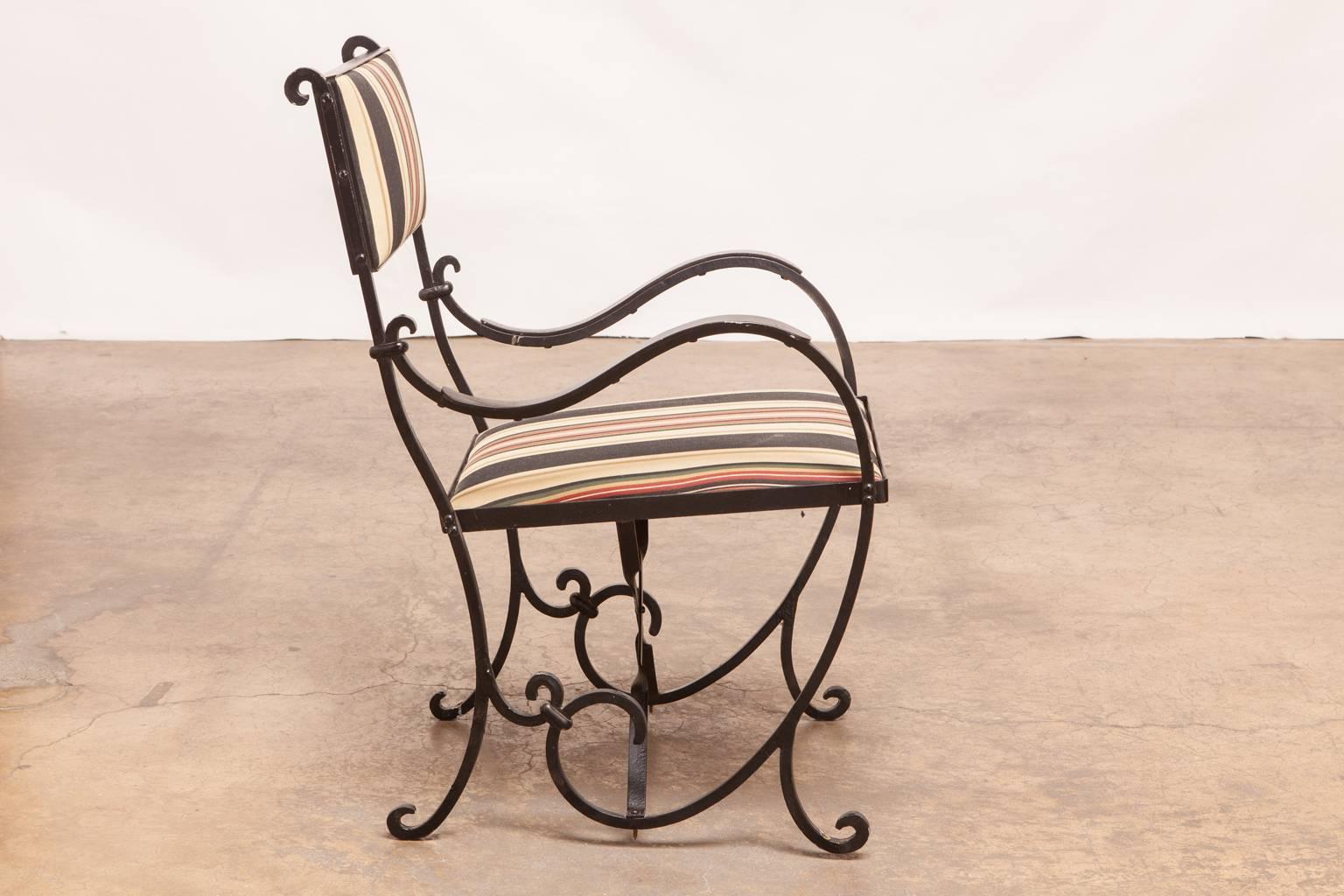 Fantastic pair of French wrought iron armchairs featuring long, graceful curved iron frames ending in decorative scrolls. These whimsical chairs appear to have been mounted to a deck or floor since each leg has a small mounting hole in the bottom.