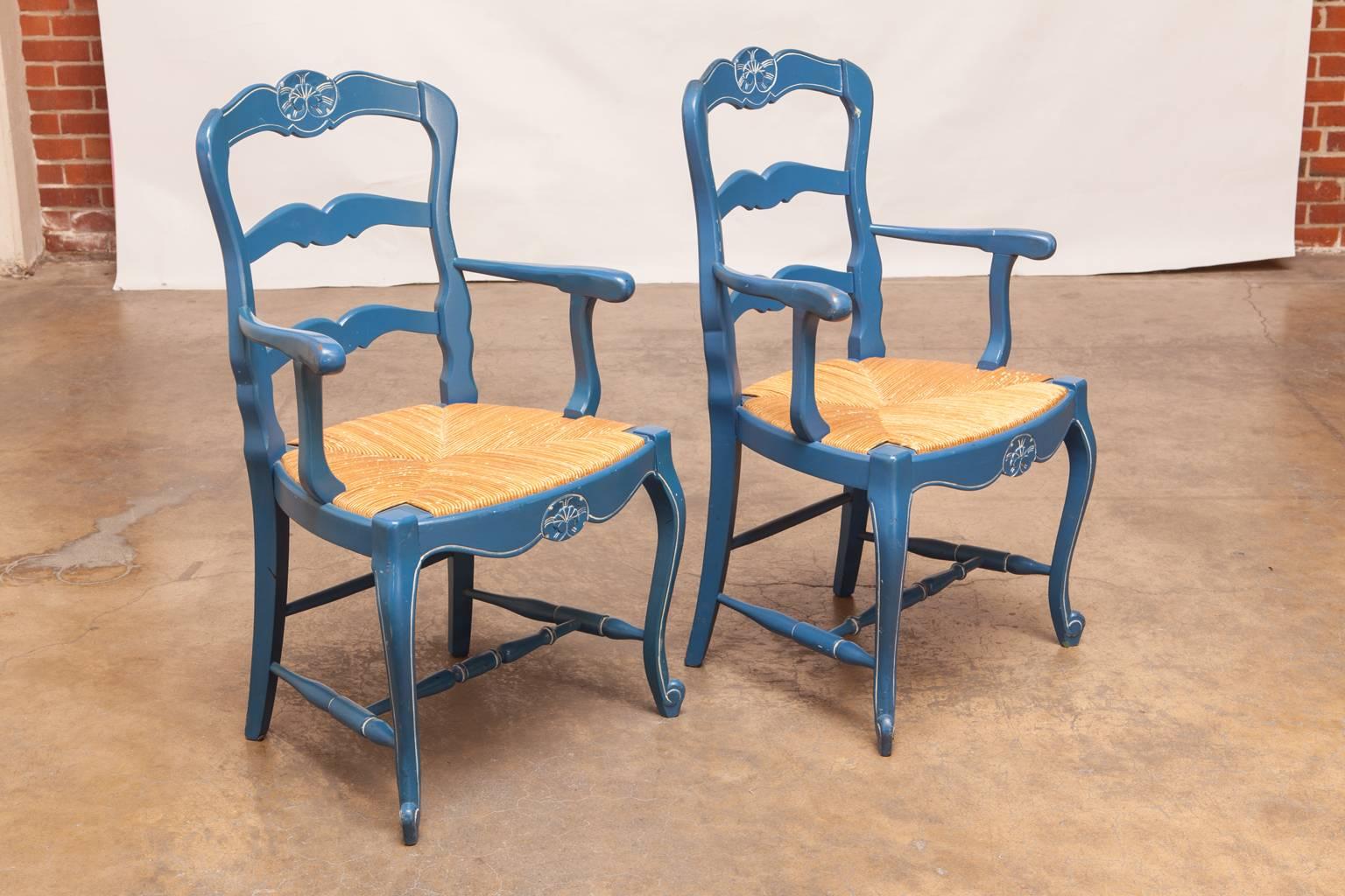 Colorful vintage carved armchairs featuring a rush bottom seat and a French blue lacquer finish. Each ladderback chair has white accent stripes and a bee motif crest. Supported by cabriole legs with scrolled feet. Made with generous proportions.