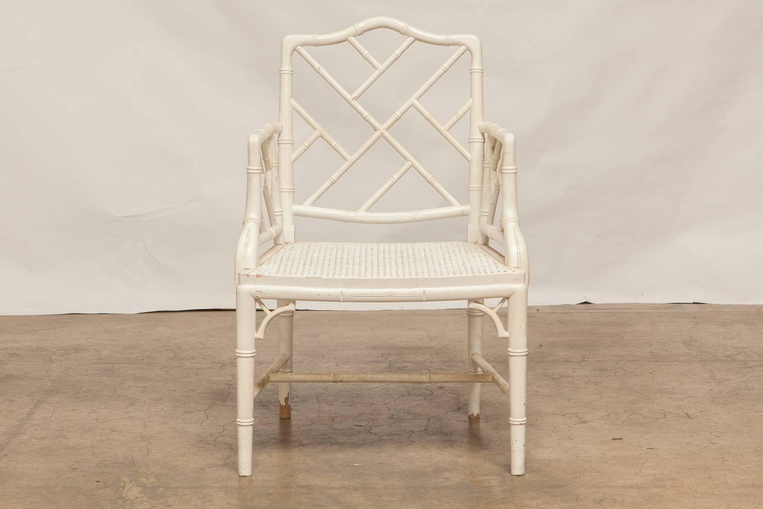 Elegant set of faux bamboo carved armchairs made in the Chinese Chippendale taste featuring a cane seat and a white lacquer finish. These armchairs have solid, tight joinery and a distressed paint finish. Made in the Classic style with open fretwork