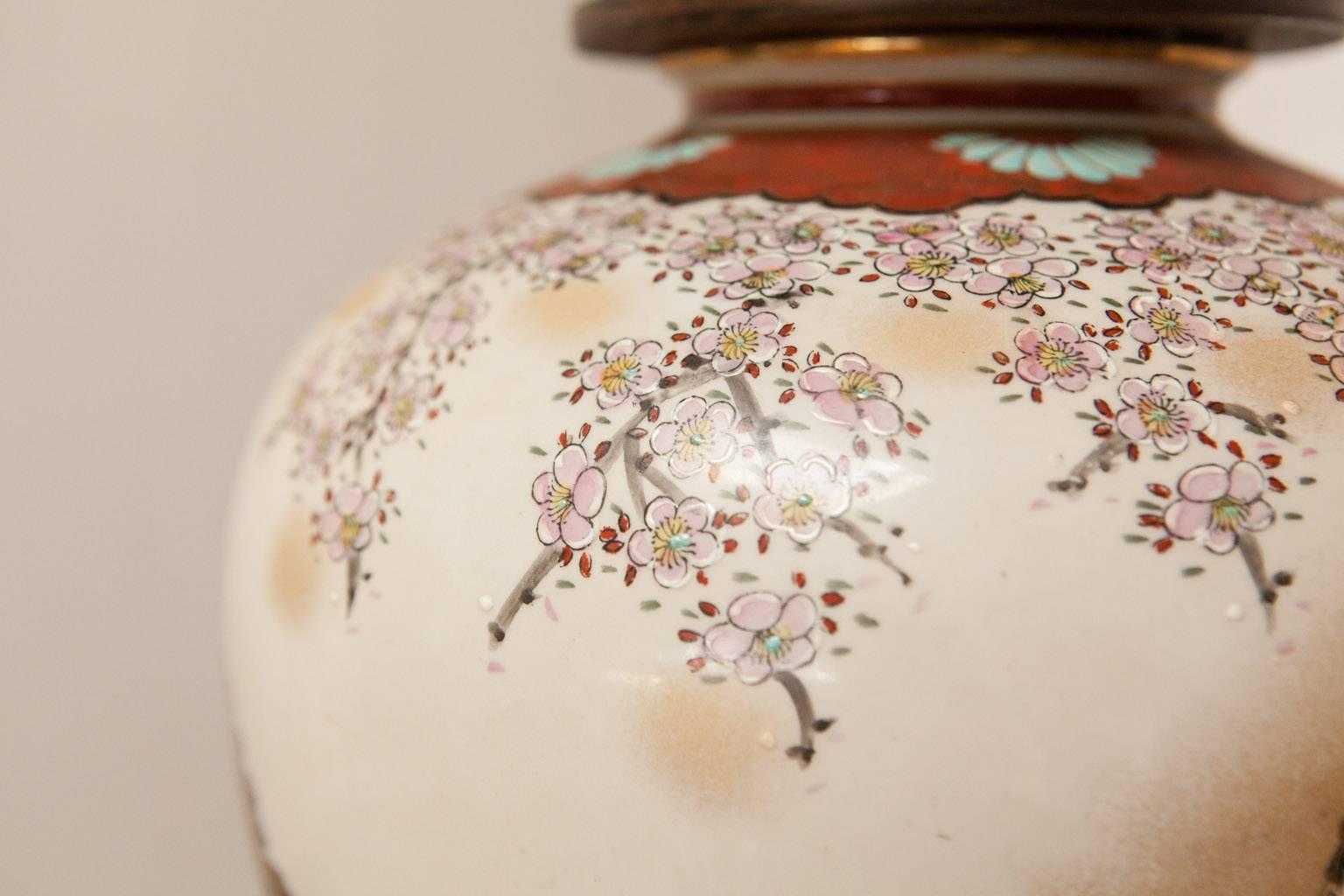 Gorgeous Japanese Satsuma style painted porcelain ginger jar converted into a table lamp with a wooden lid and set on a brass pedestal with a wood base. Produced by Frederick Cooper of Chicago. Depicts idyllic Asian social scenes with colorful