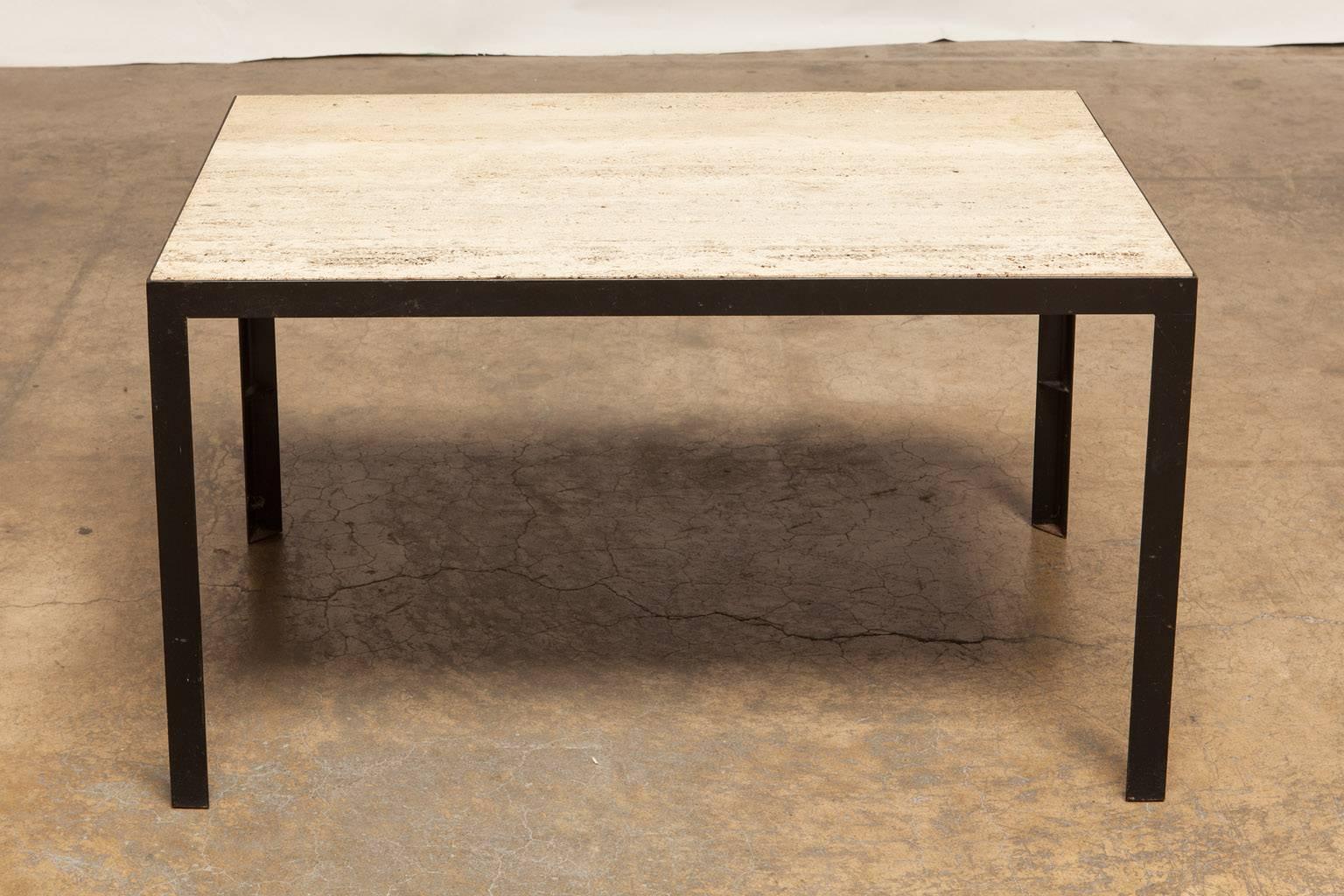 Minimalist Mid-Century coffee table featuring a 1.5" slab of travertine set into a black iron frame. Supported by straight squared legs and made in Italy. The large rectangle of travertine has a natural unfilled finish and an elegant simple