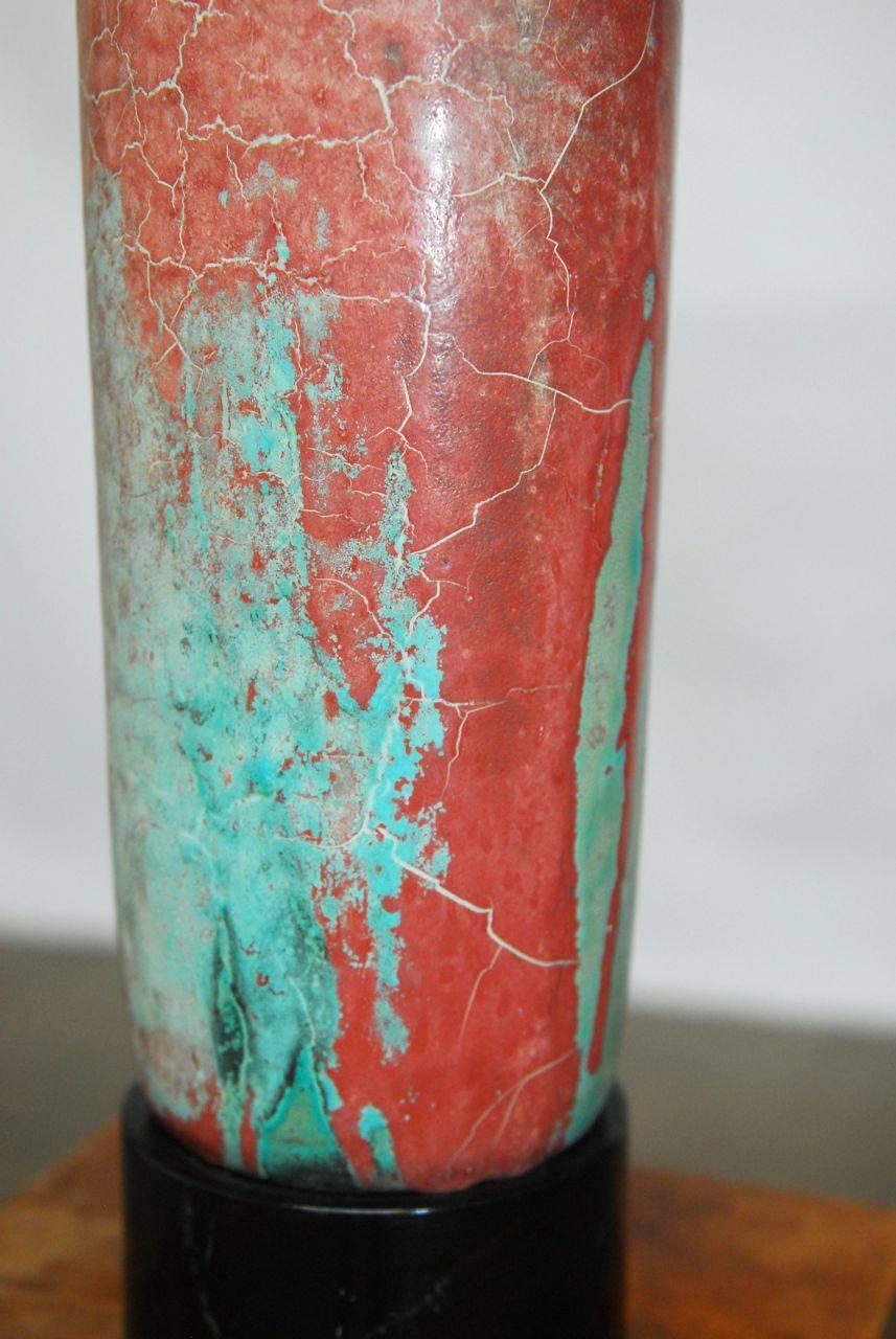 Magnifique vase en céramique moderne danoise du milieu du siècle produit par Mobach à Utrecht. Cette pièce présente une forme cylindrique façonnée à la main et un glaçage craquelé fantastique dans une gamme de rouges sourds avec des verts sarcelle