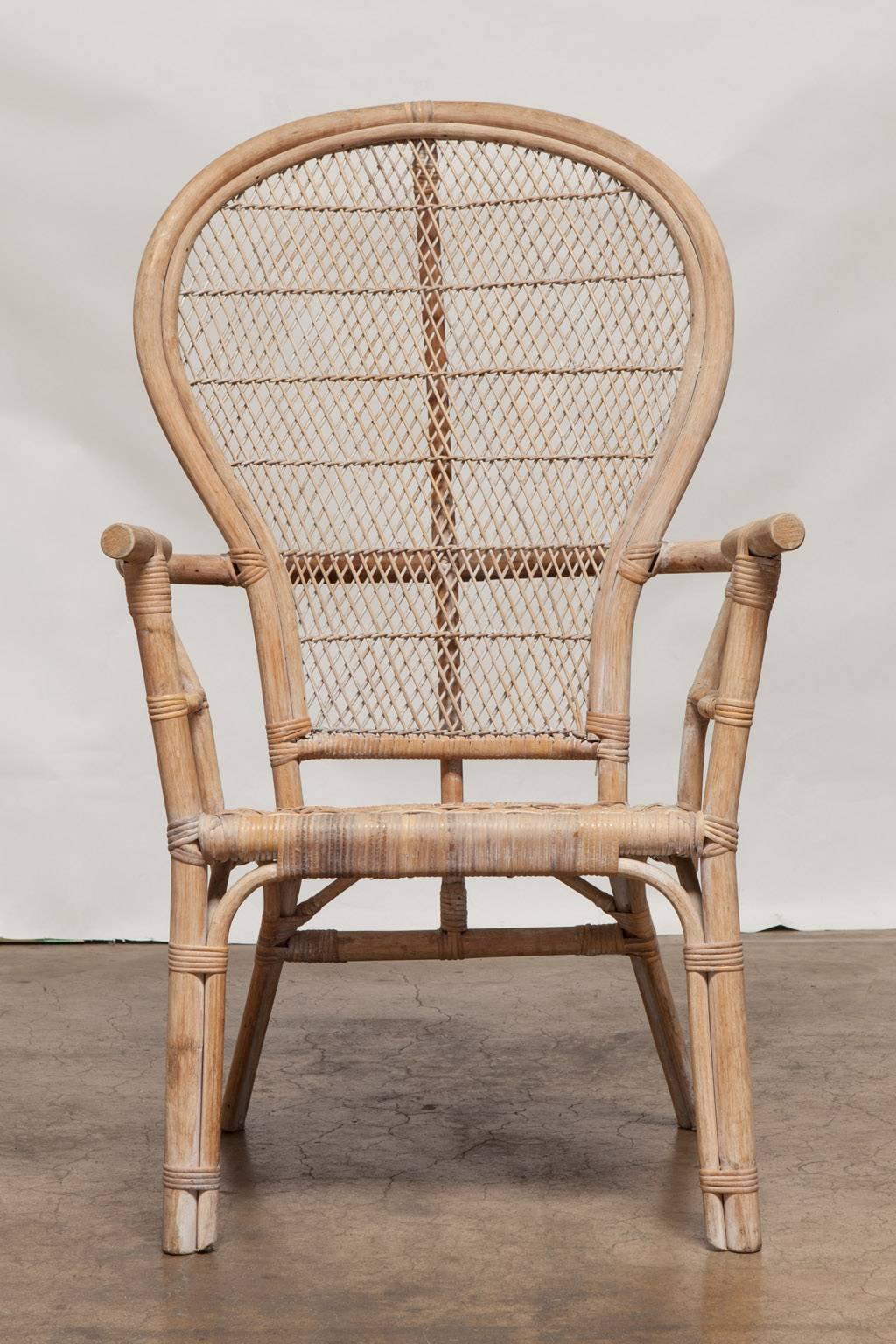 Distinctive rattan peacock armchairs featuring a fan shaped back with a woven fretwork design. Serpentine shaped arms with a woven seat are supported by round rattan legs.