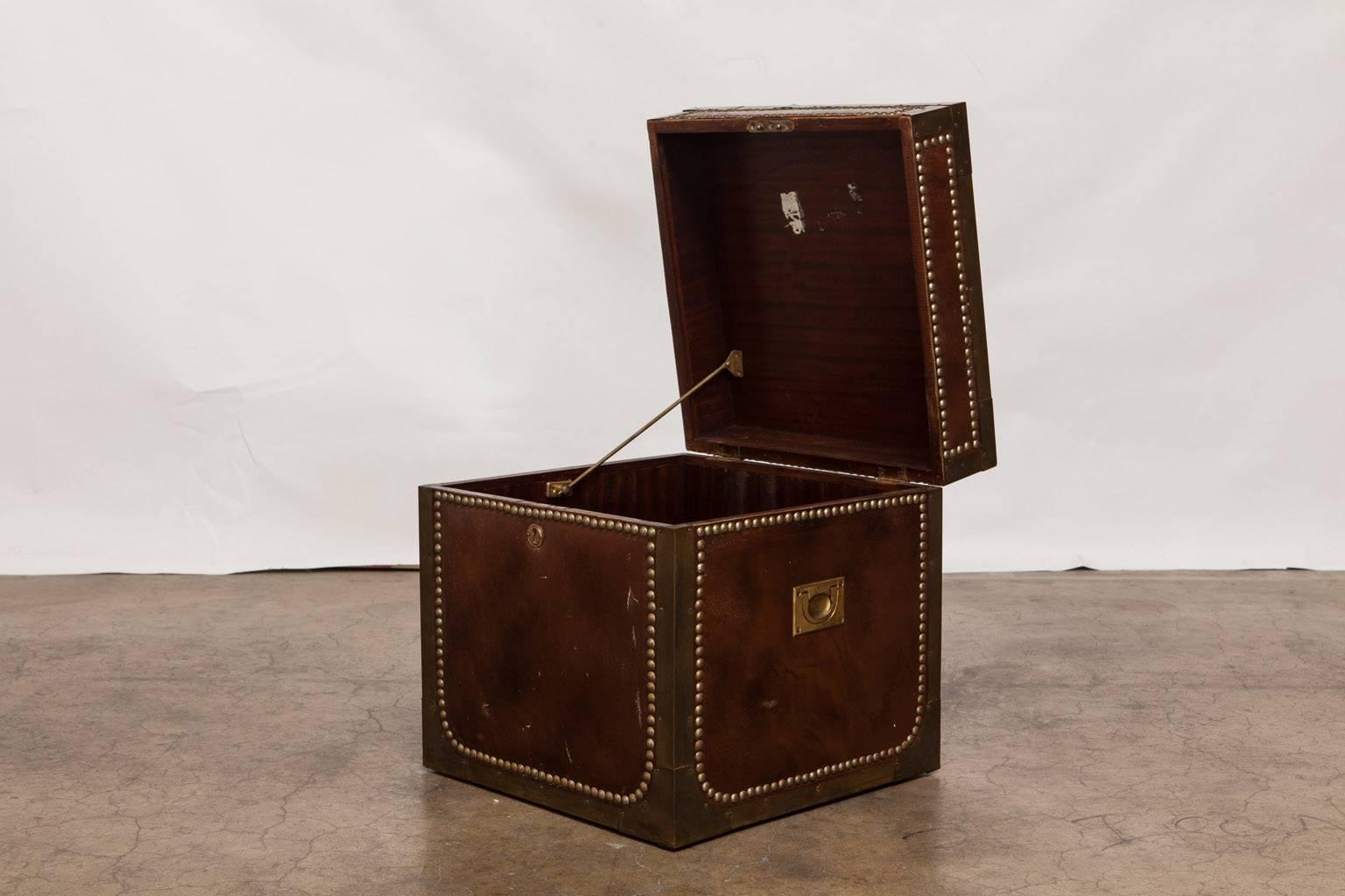 English Regency brass and leather Campaign style box featuring brass nailhead trim and strapping. Opens for storage and has a hinged lid with brass hardware and a mahogany interior. Brass Campaign handles on each side and clad in brown leather.