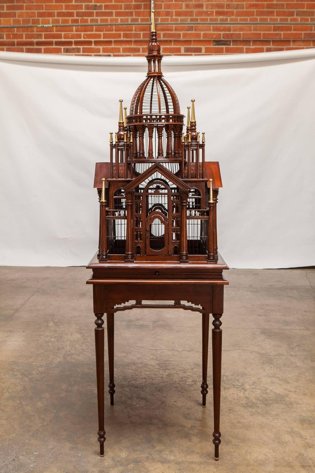 Rare Maitland-Smith architectural bird cage on Stand featuring hand-carved mahogany Baroque style palatial structure with a porticoed temple and brass spires on the tops. Mounted on a square table with elegant tapered legs and a carved apron.