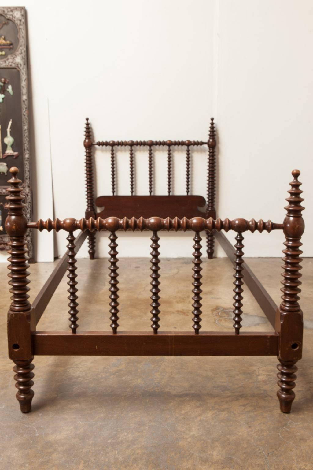 Matched pair of Mahogany spool beds made in the Jenny Lind style featuring lovely turned spindle columns with graduated finials and toupie feet. Headboard and footboard are mortised to the end rails and the finish is original with minor scratches in