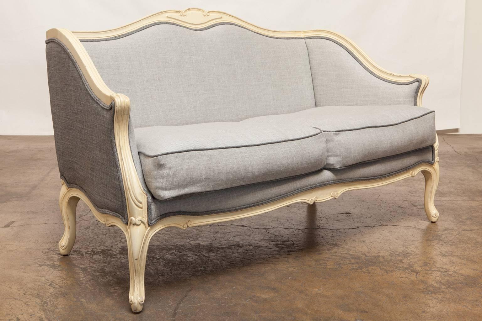 Fantastic pair of matching French Louis XV style painted walnut settees featuring a new two-tone French organic linen upholstery. The back of the settees has a darker gray linen used as an accent to the front with a double welt border all around as