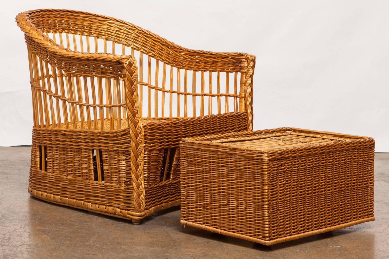 Stylish pair of rattan and stick wicker club chairs or lounge chairs and ottoman by Mcguire featuring a barrel-back form. The wicker covered frames have braided arms and decorative windows in the bases. Well-made with a lovely profile these chairs