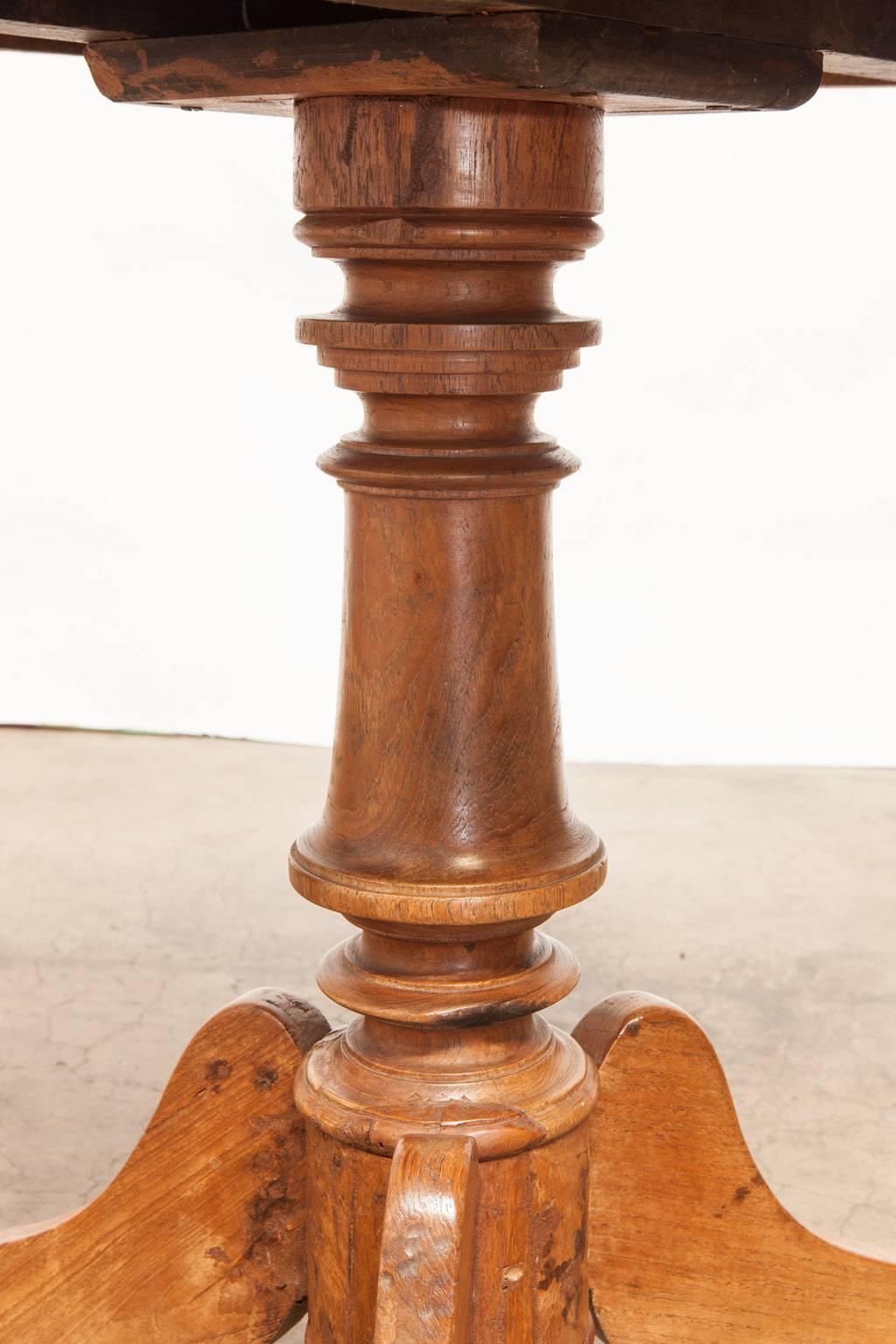 Rustic carved walnut side table made in the George III period featuring a thick turned column supported by graceful scrolled legs. Lovely patina lightened from age with a strong sturdy base.