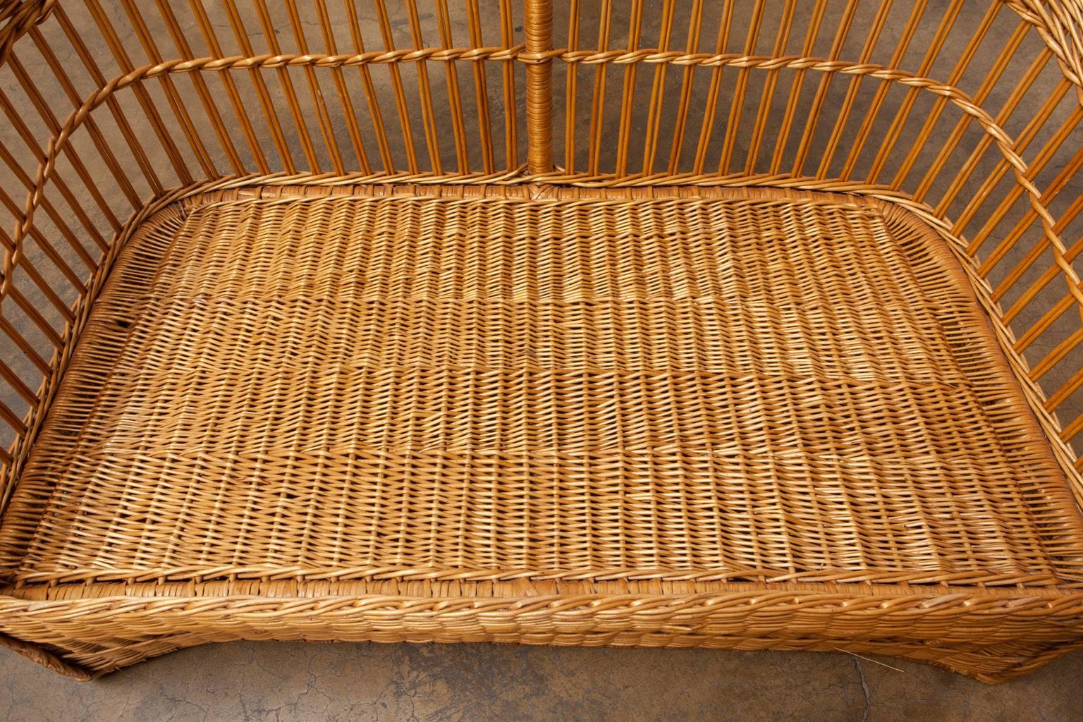 Stylish rattan and stick wicker settee by McGuire featuring a round barrel back shape. The wicker covered frames have braided arms and decorative windows in the base. Well made by famous rattan furniture maker McGuire, San Francisco. This sofa