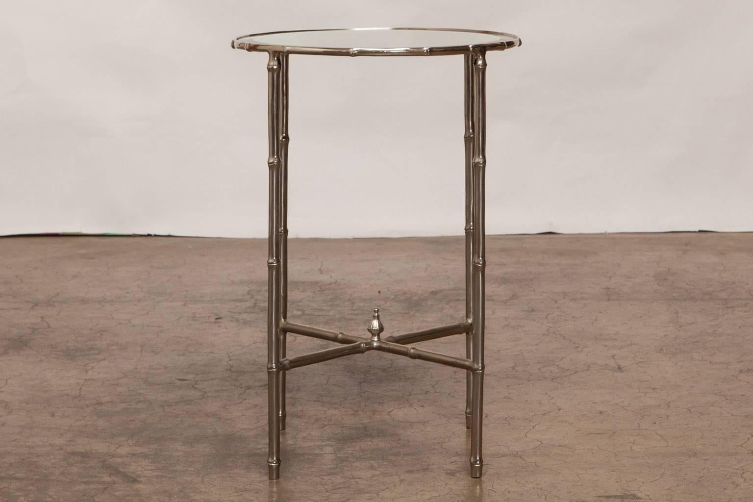 The perfect chrome nickel faux bamboo drink or side table with a round beveled mirror top. Features four faux bamboo legs attached by a cross stretcher with an acorn finial. Made in the French Maison Jansen style and attributed to Mastercraft.