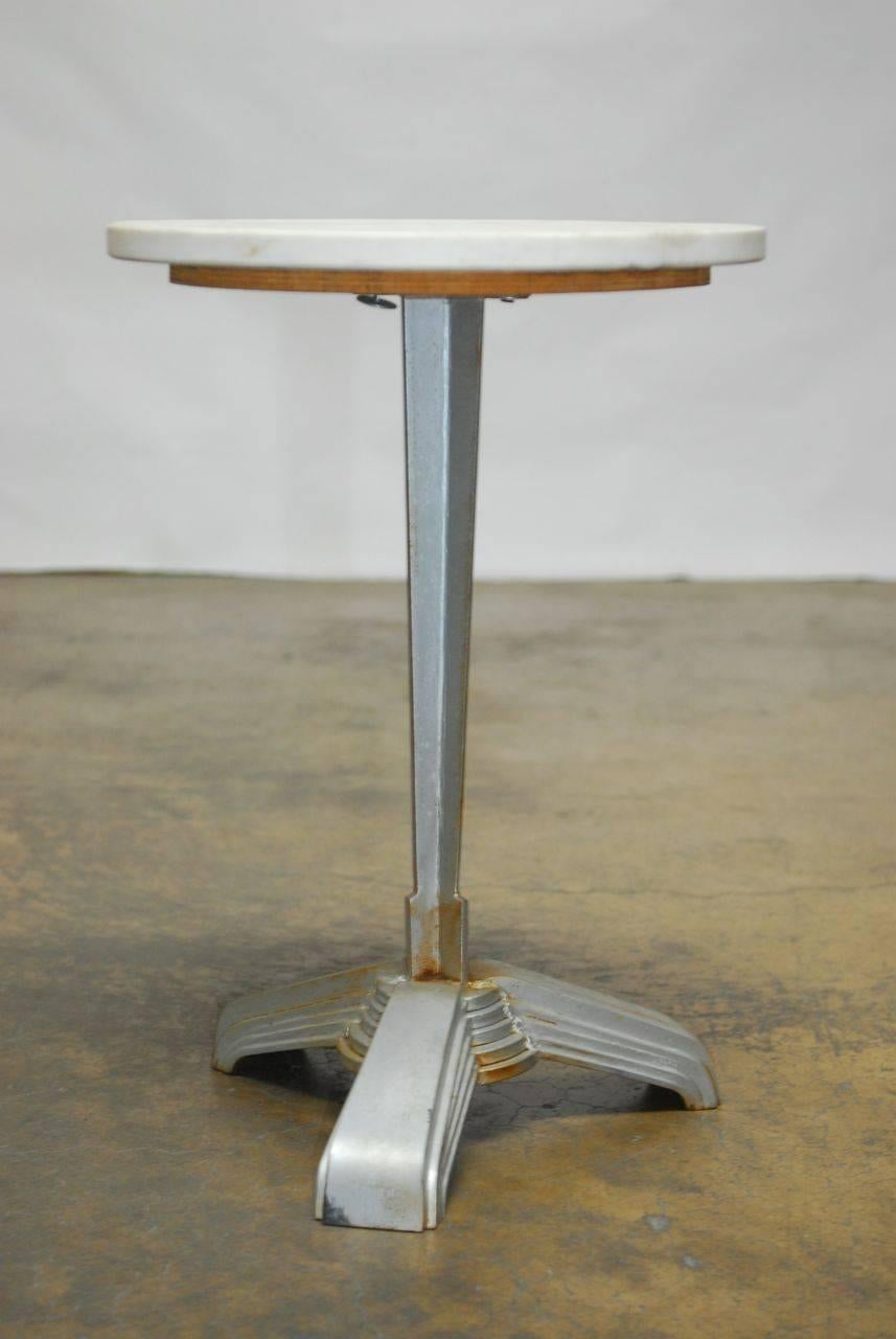 Fantastic iron bistro or drink table featuring a round marble top made in the Art Deco style with a tapered column and architectural base. Finished in a period correct silver with an aged patina. This unique table captures the artistic design of the