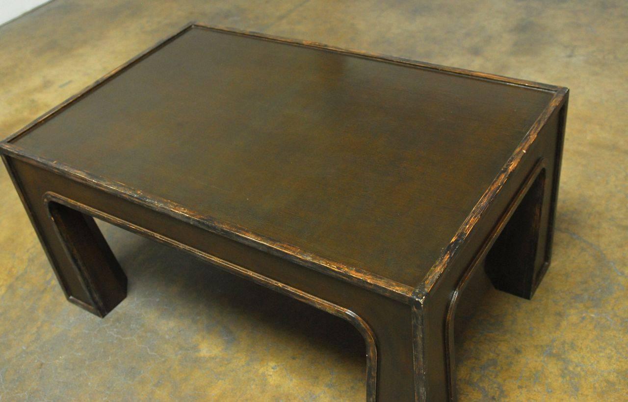 Unusual Chinese lacquered coffee table featuring a modern architectural design that has a rectangular shape top with sharp corners supported by substantial flared legs and deep green or brown in color.