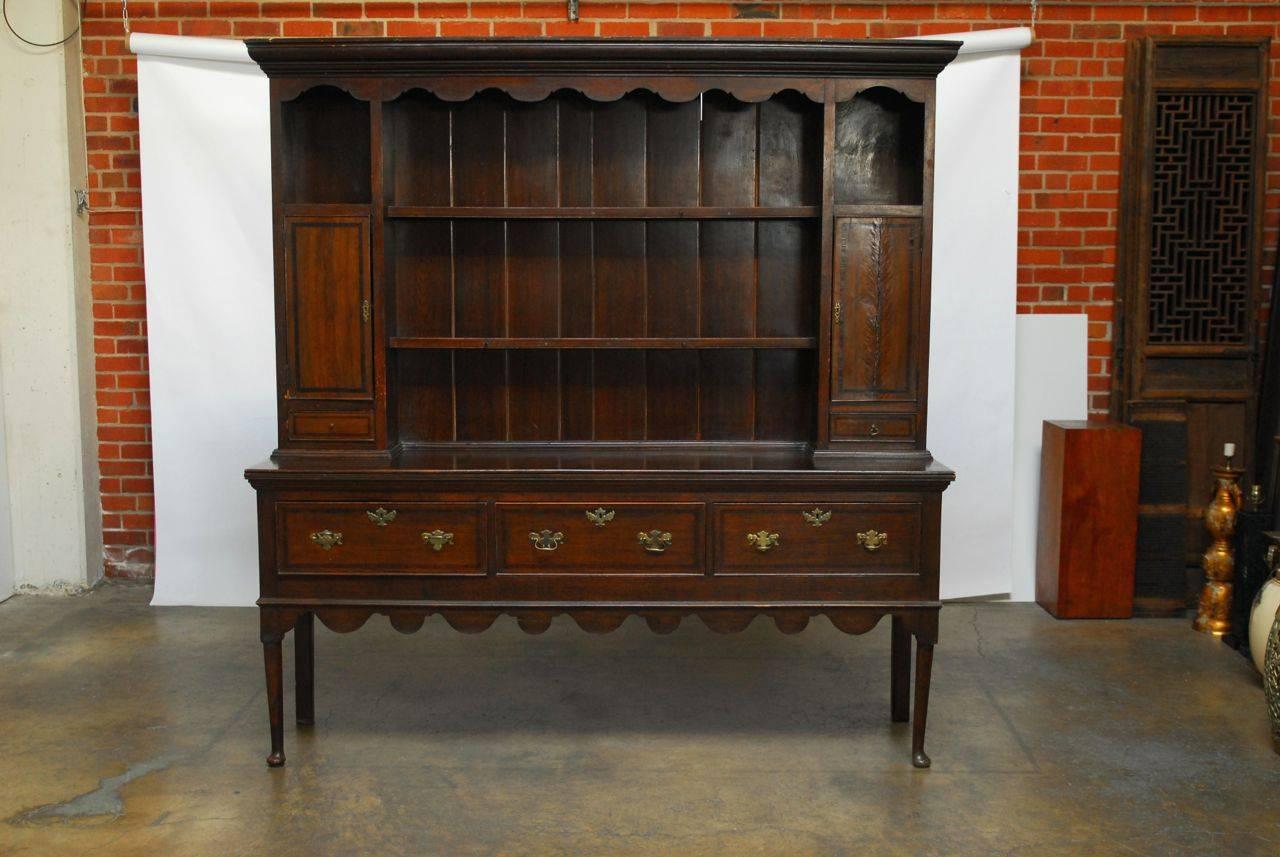 Handsome late 18th century two-part English oak welsh server or buffet featuring an upper corniced cupboard rack with two shelves and two small cabinets. Each cabinet door is decorated with a simple border inlay as well as the two small drawer