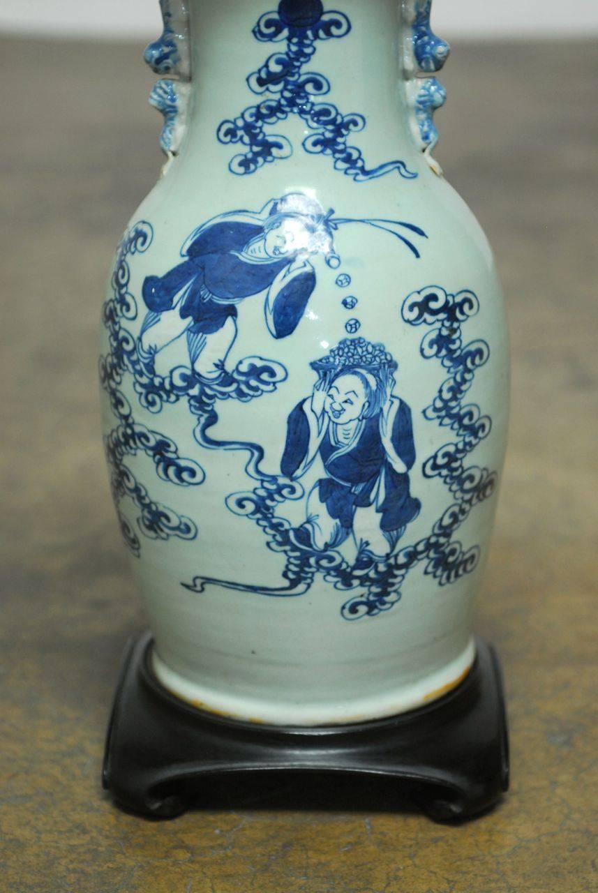 Whimsical Chinese under glazed blue and white porcelain vase featuring the Buddhist immortal laughing twins Hehe Erxian who represent harmony and union and bestow their blessings on marriages. They are depicted in a playful scene on the front of the