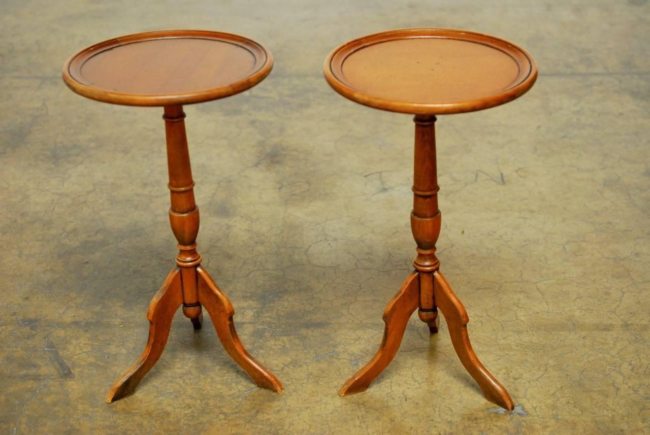 Charming pair of diminutive Italian tripod drink tables made of mahogany in the Georgian taste. Features a round top with a raised dish edge and a turned column supported by three legs. Original use was probably as candle stands.