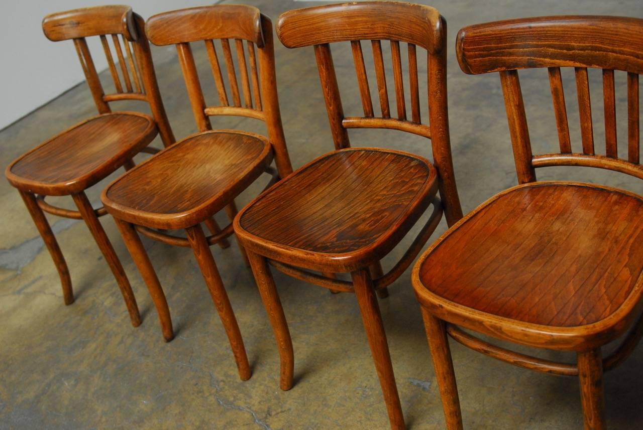 Mid-Century set of four Thonet design bistro chairs made of beech with a pine seat. Made in Krakow, Poland and labelled polish Bentwood Furniture Industry. Comfortable with a lovely warm patina.