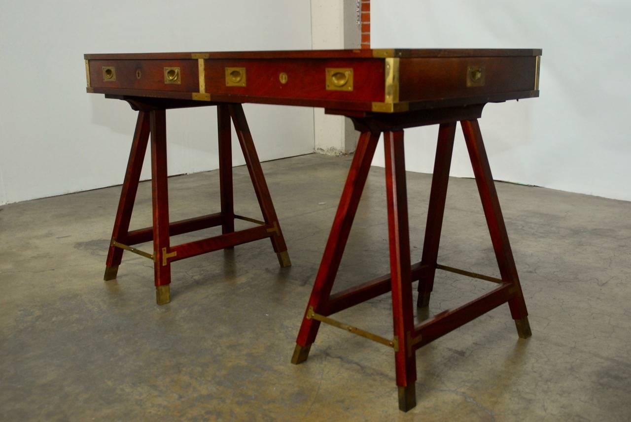 Exquisite British campaign desk featuring Classic sawhorse folding legs. The top of the desk is fitted with a black tooled leather writing surface and the case has brass corner hardware and pulls fitted to the highest quality of craftsmanship. The