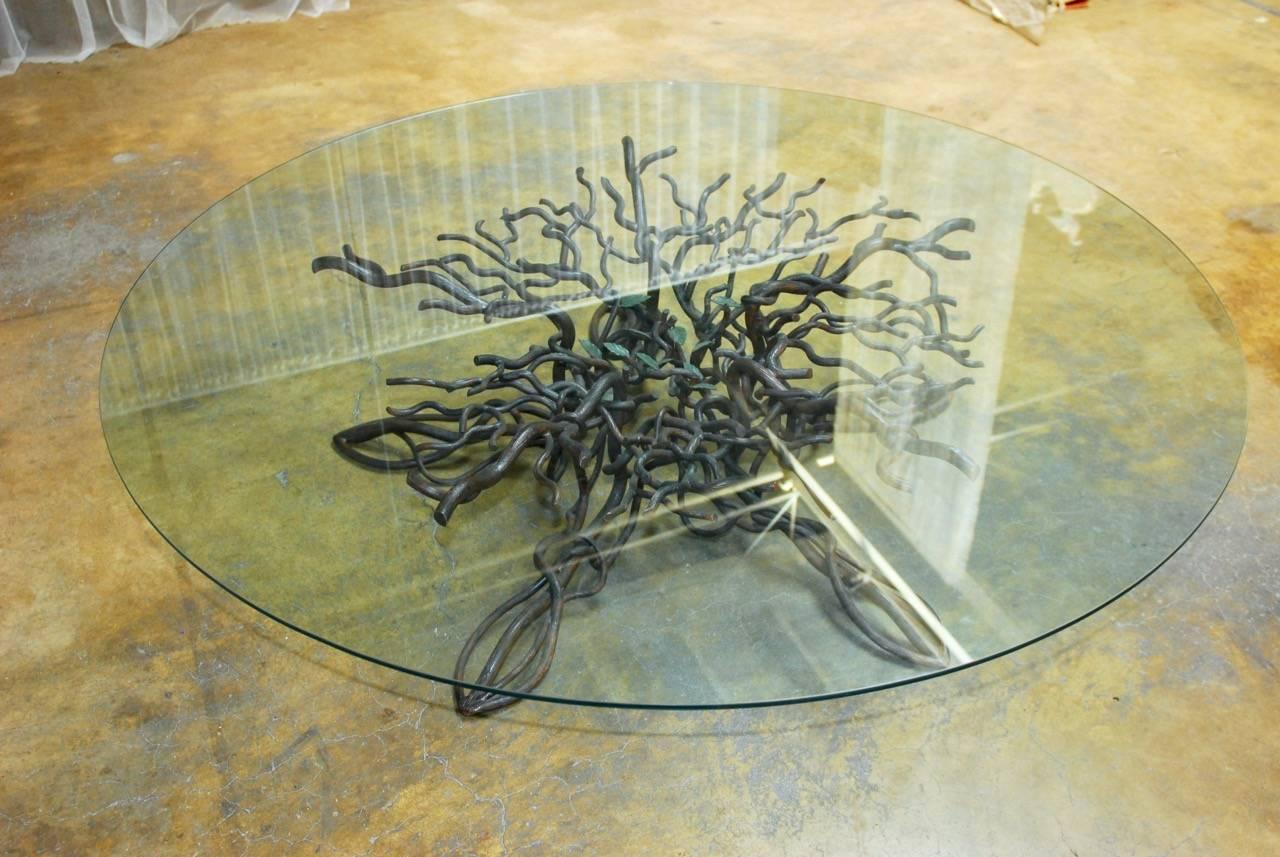 Phenomenal hand-forged wrought iron cocktail table featuring a Giacometti inspired star-shaped twisted tree root base that grows out of the ground and climbs under a massive round pane of glass. Made by a California artisan using thick hand-cut iron