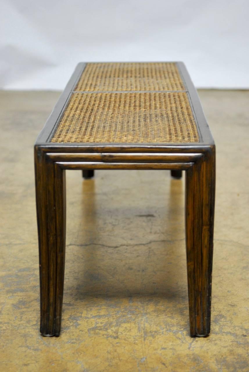 Handsome mahogany bench with cane seat panels featuring a reeded frame and legs. The legs are saber splayed form and the frame has a rich finish. Designed by Eleanor Forbes for McGuire.
