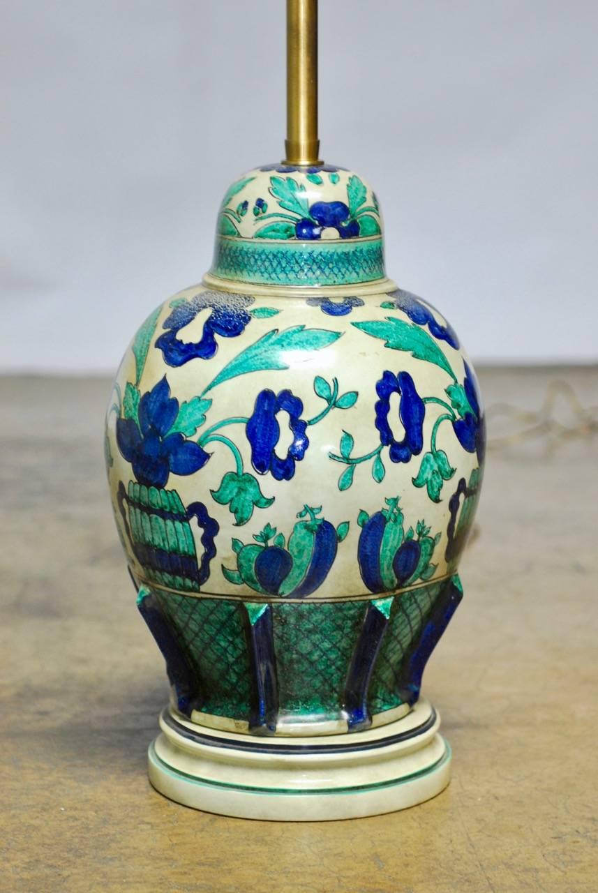 Large Italian ceramic lidded urn table lamp by Marbro Lamp Co. featuring a faience hand-painted body with Indigo blue flowers and foliage. Supported by a turned ceramic plinth and equipped with brass hardware and original milk glass diffuser. Signed