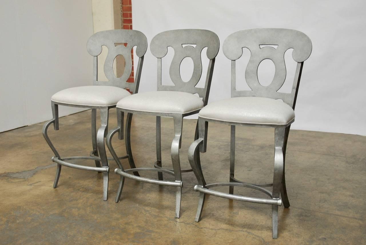 Chic set of Biedermeier style barstools executed in a modern taste. Featuring metal construction with an exaggerated cabriole leg and a neoclassical style back that give them a whimsical look. Upholstered in a shimmery linen with a welt border. Fine