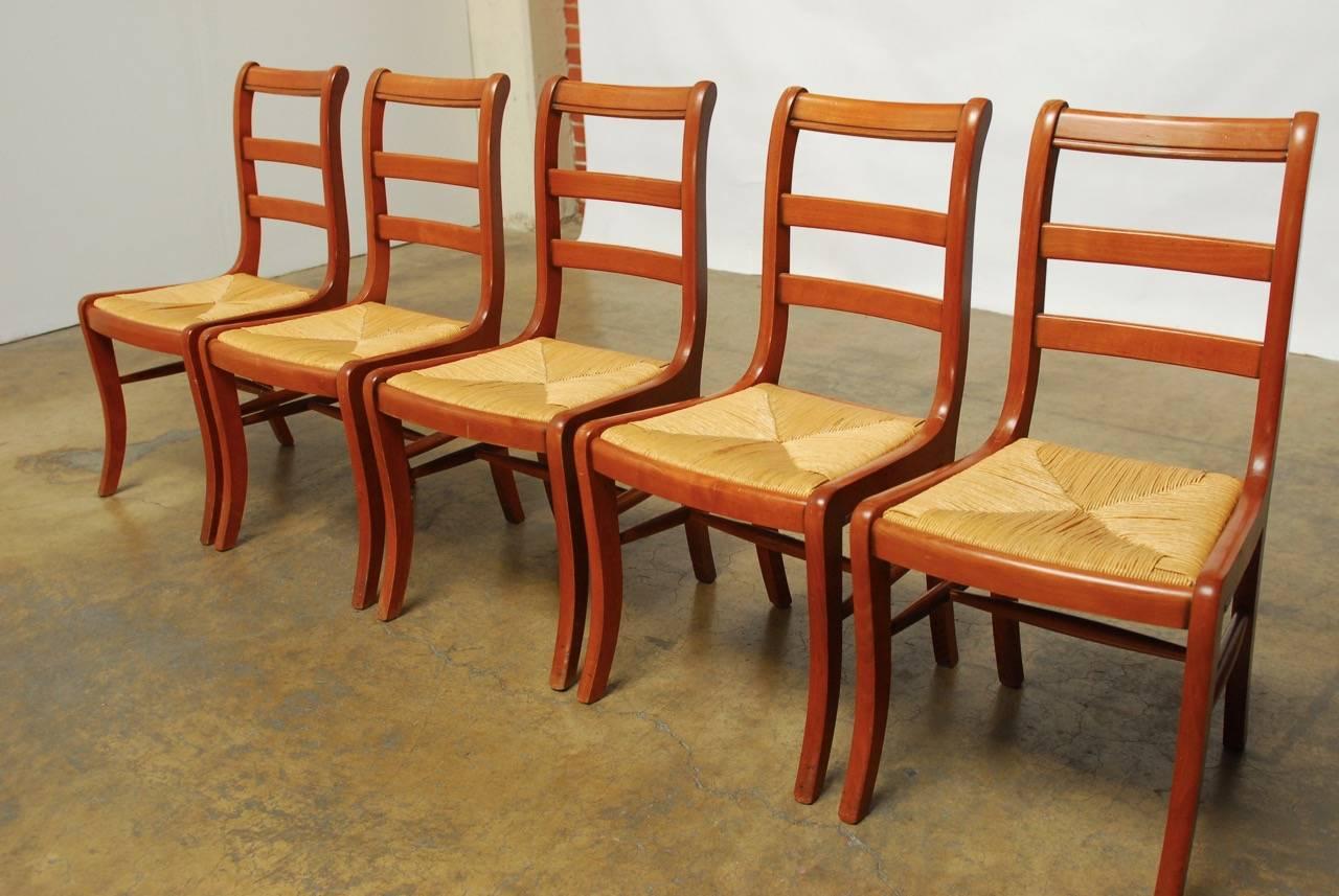 Large set of 45 dining chairs made by Grange in France. Featuring a Classic Klismos form with sabre legs in front and a comfortable handmade rush seat. Each chair has a two rail ladder back design and 
