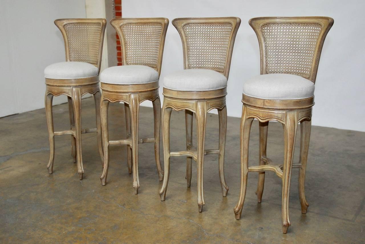 Exquisite set of Swedish Gustavian Style petite barstools featuring a Classic neutral grey lacquer finish over a distressed wood. Newly upholstered in an organic cream linen. These stools have a beautifully carved frame with a hand-caned back.