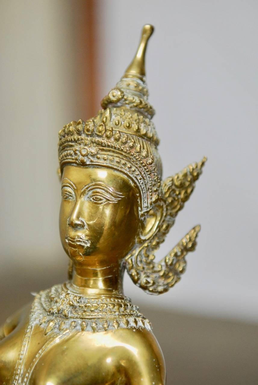 Elaborate Thai gilt bronze Buddhist statue of a khon dancer in a dancing posture. She is depicted wearing a high tiara, jewels, and a sampot. Kneeling on a lotus covered Stand this thickly cast bronze has a rich gilt finish.