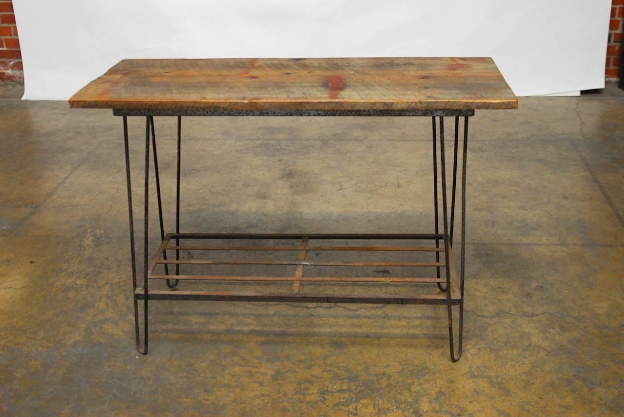 Rustic French Industrial style console table featuring an iron base with hairpin legs and a lower shelf. Topped with two planks of distressed wood. This would also make a great sofa or entry table.